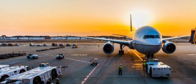 A large passenger jet is parked on the tarmac at an airport at sunset.