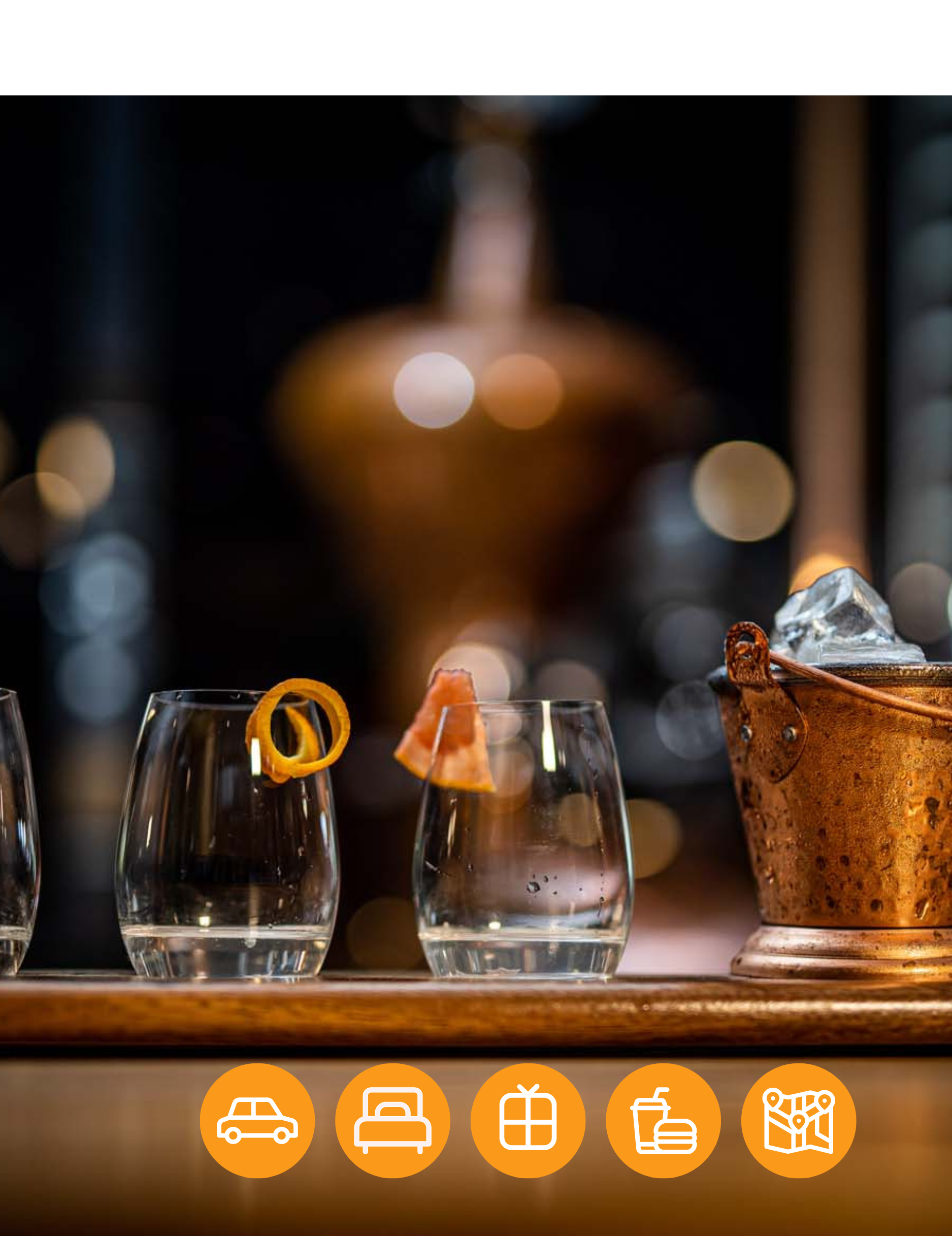 A row of glasses sitting on top of a wooden table next to a bucket of ice.