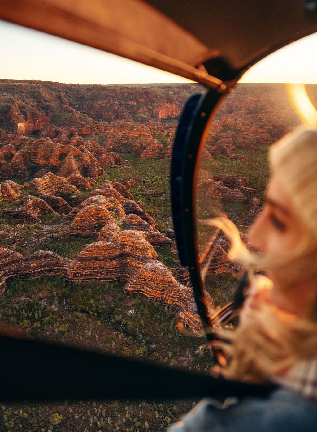 A woman is looking out of the window of a helicopter.