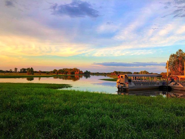 A boat is docked in the middle of a river at sunset.