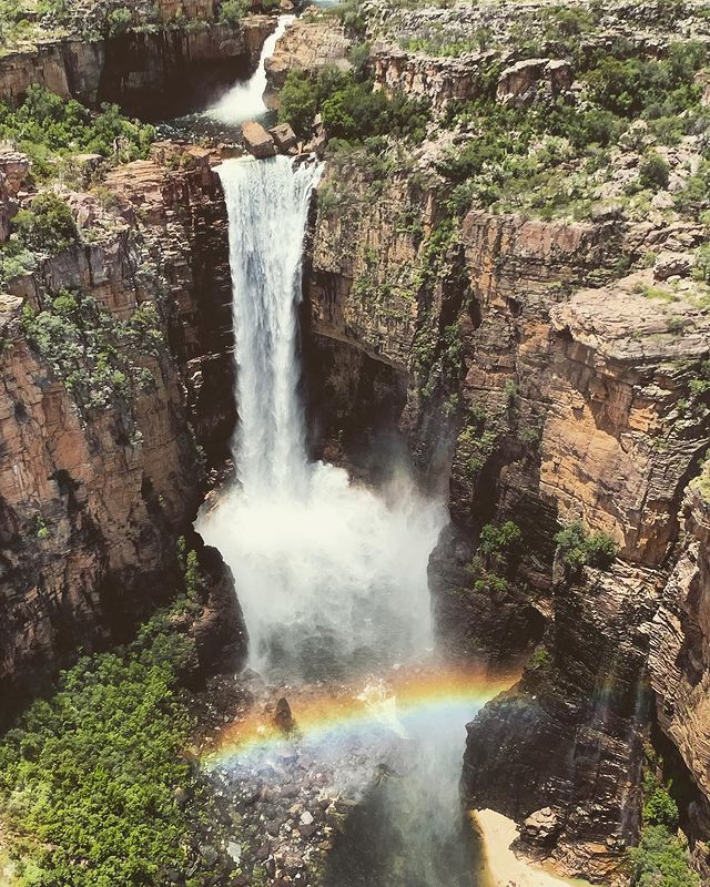 A waterfall with a rainbow in the middle of it