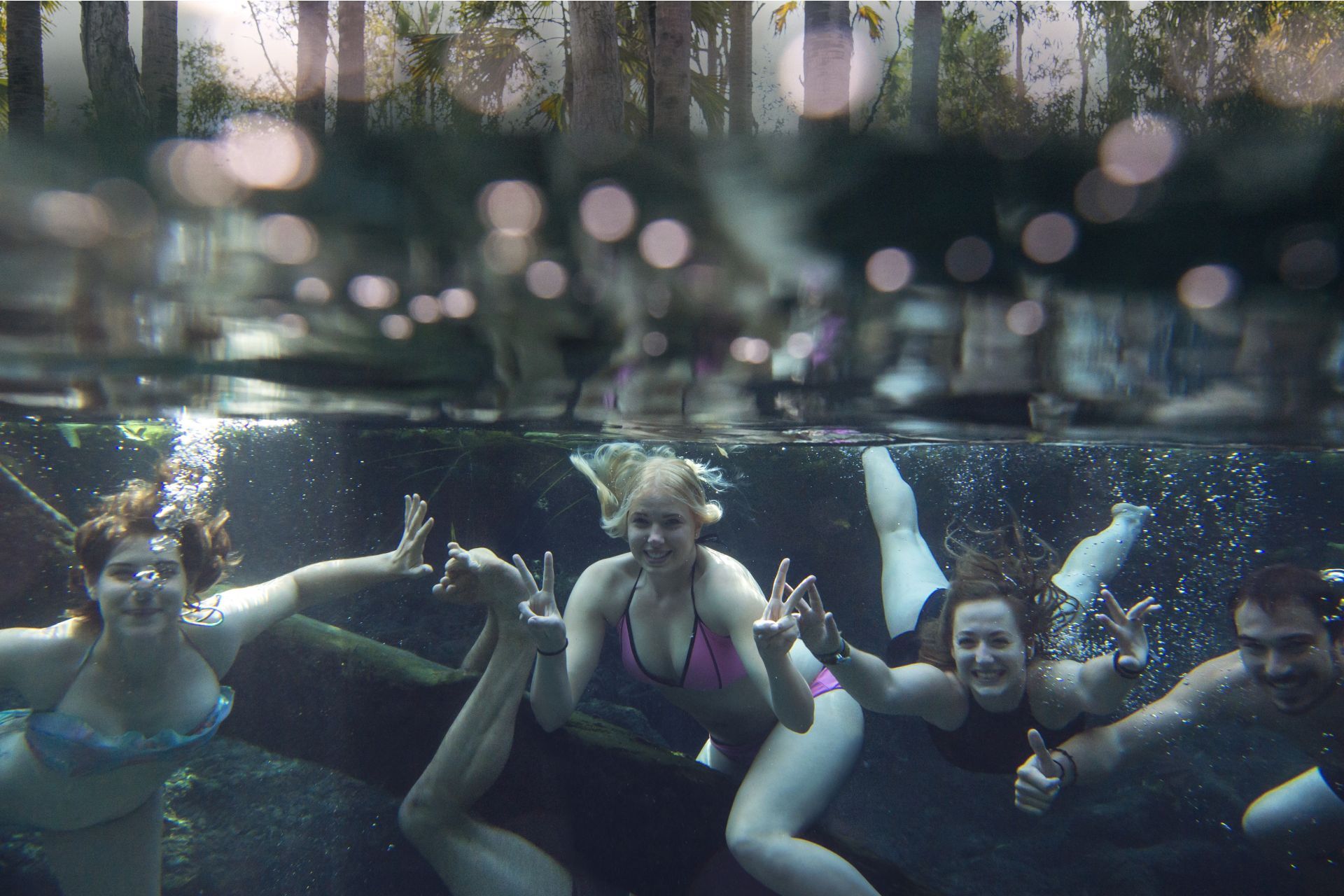 A group of women are swimming underwater in a pool
