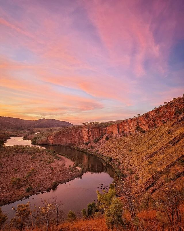 A river flowing through a canyon with a sunset in the background.