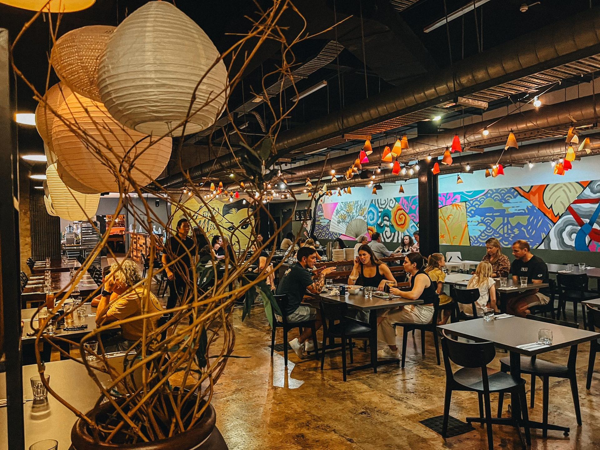 A restaurant filled with people sitting at tables and chairs.