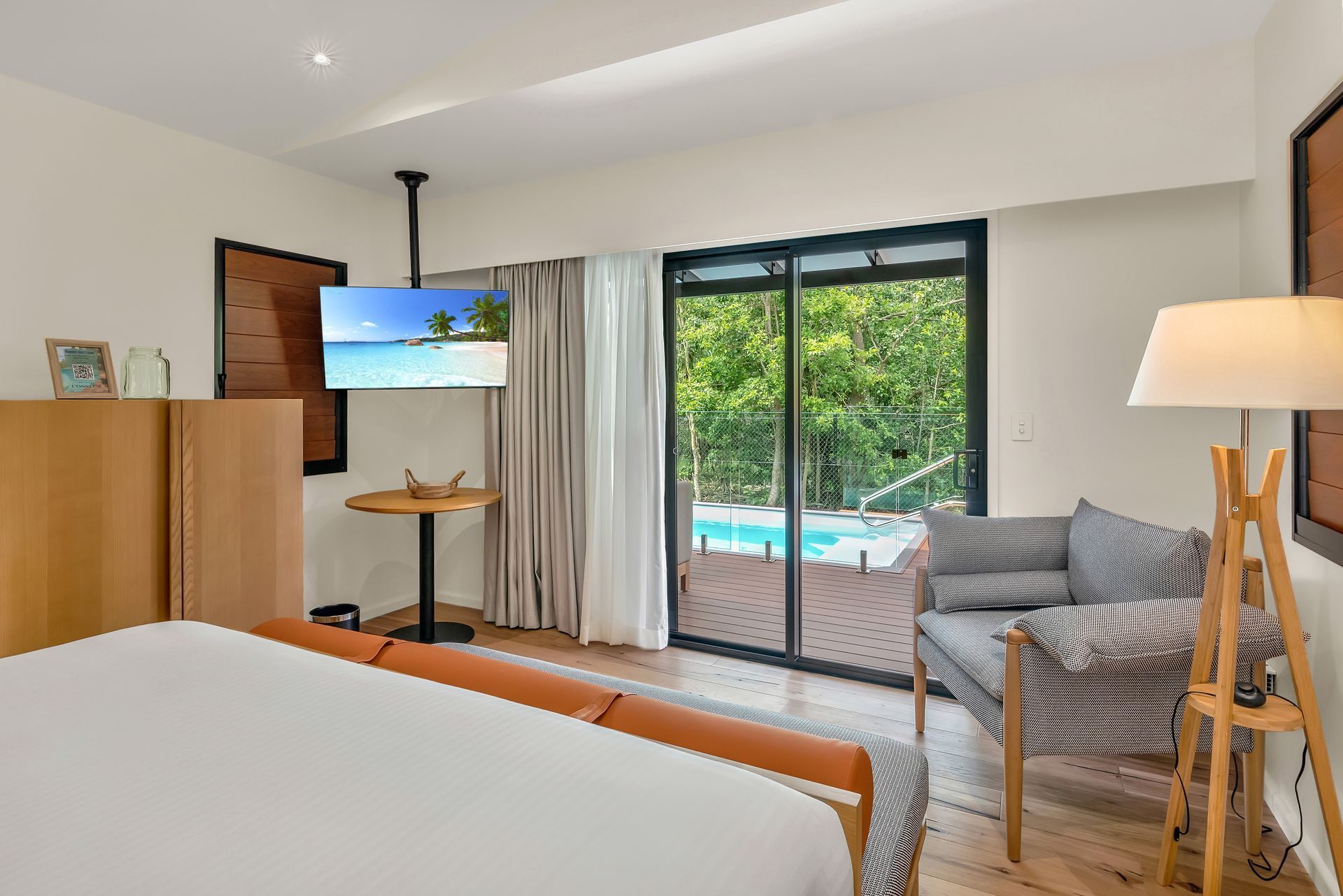 A hotel room with a bed , chair , table and television.