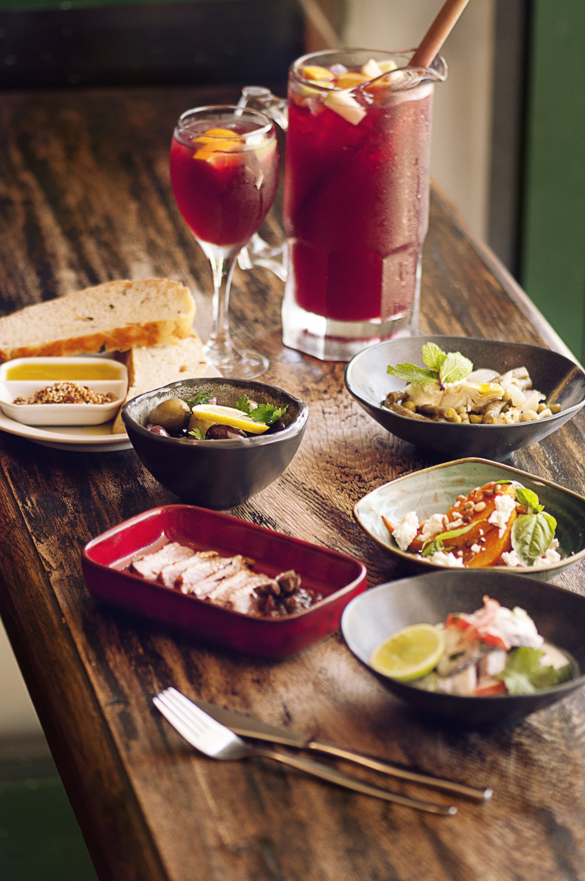 A wooden table topped with bowls of food and drinks.
