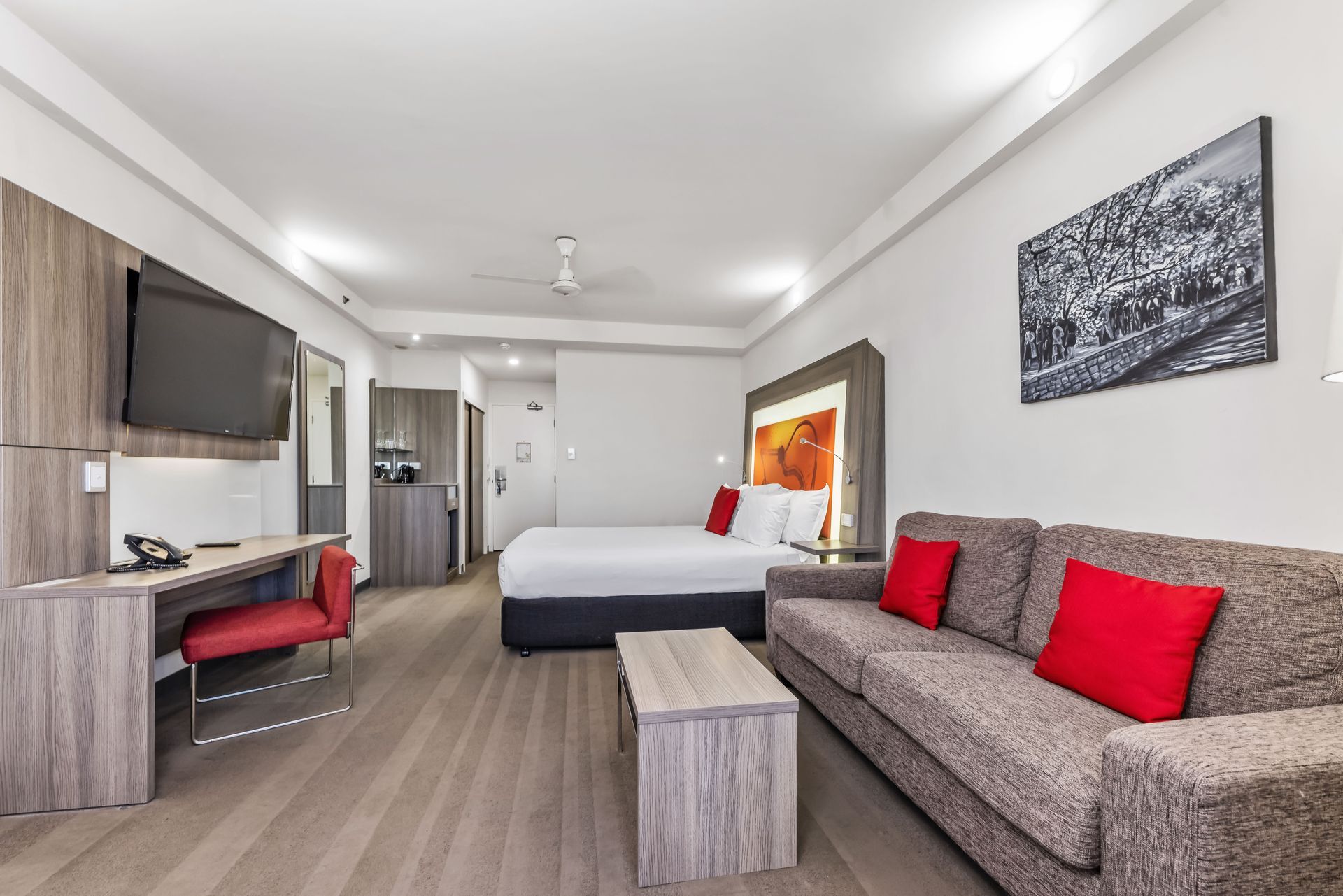 A hotel room with a bed , couch , desk and television.