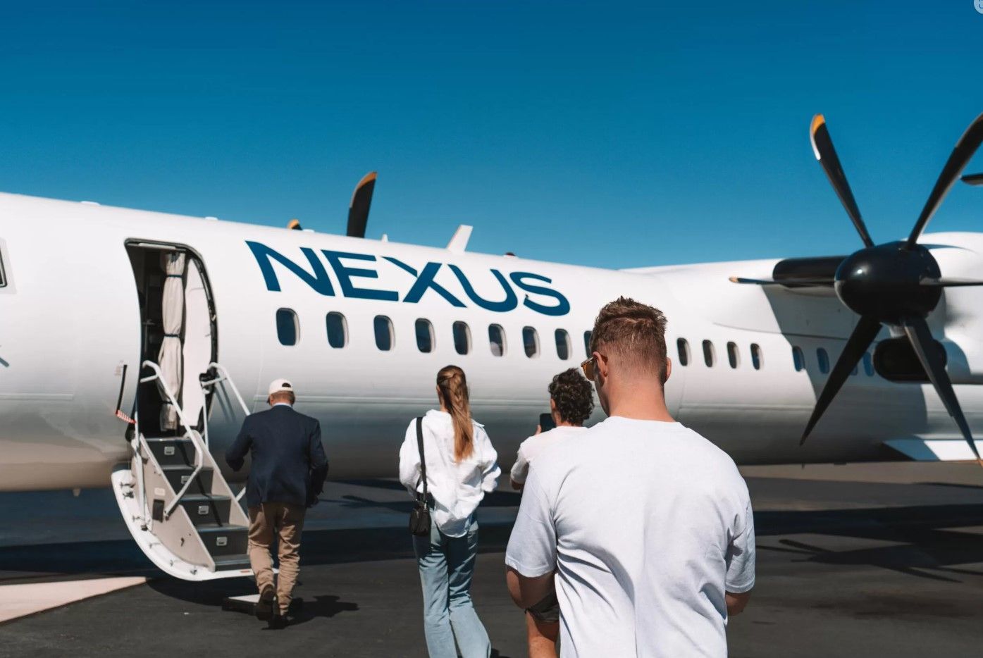 A group of people are boarding a nexus airplane.