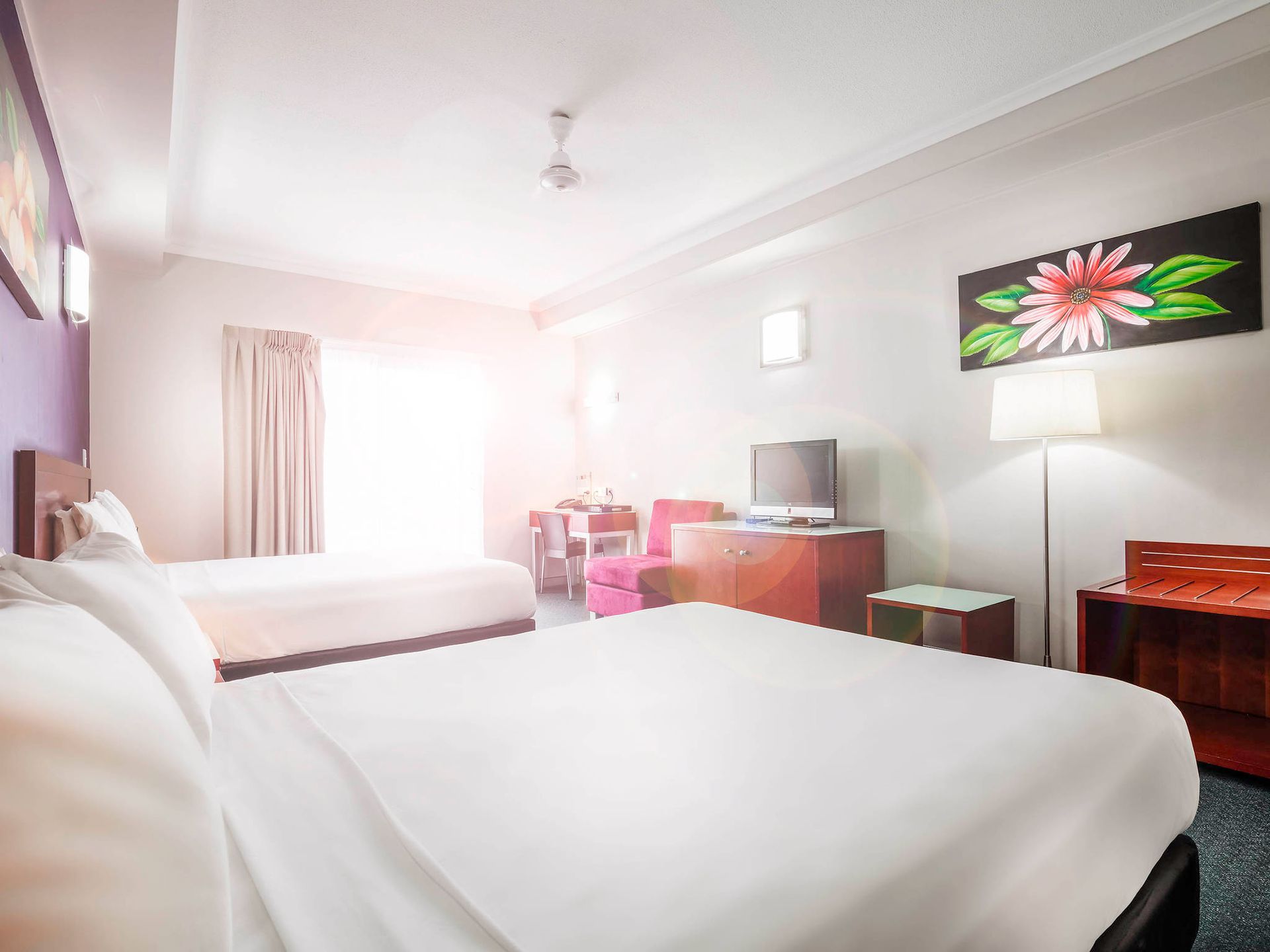 A hotel room with a king size bed , television , nightstand and purple walls.