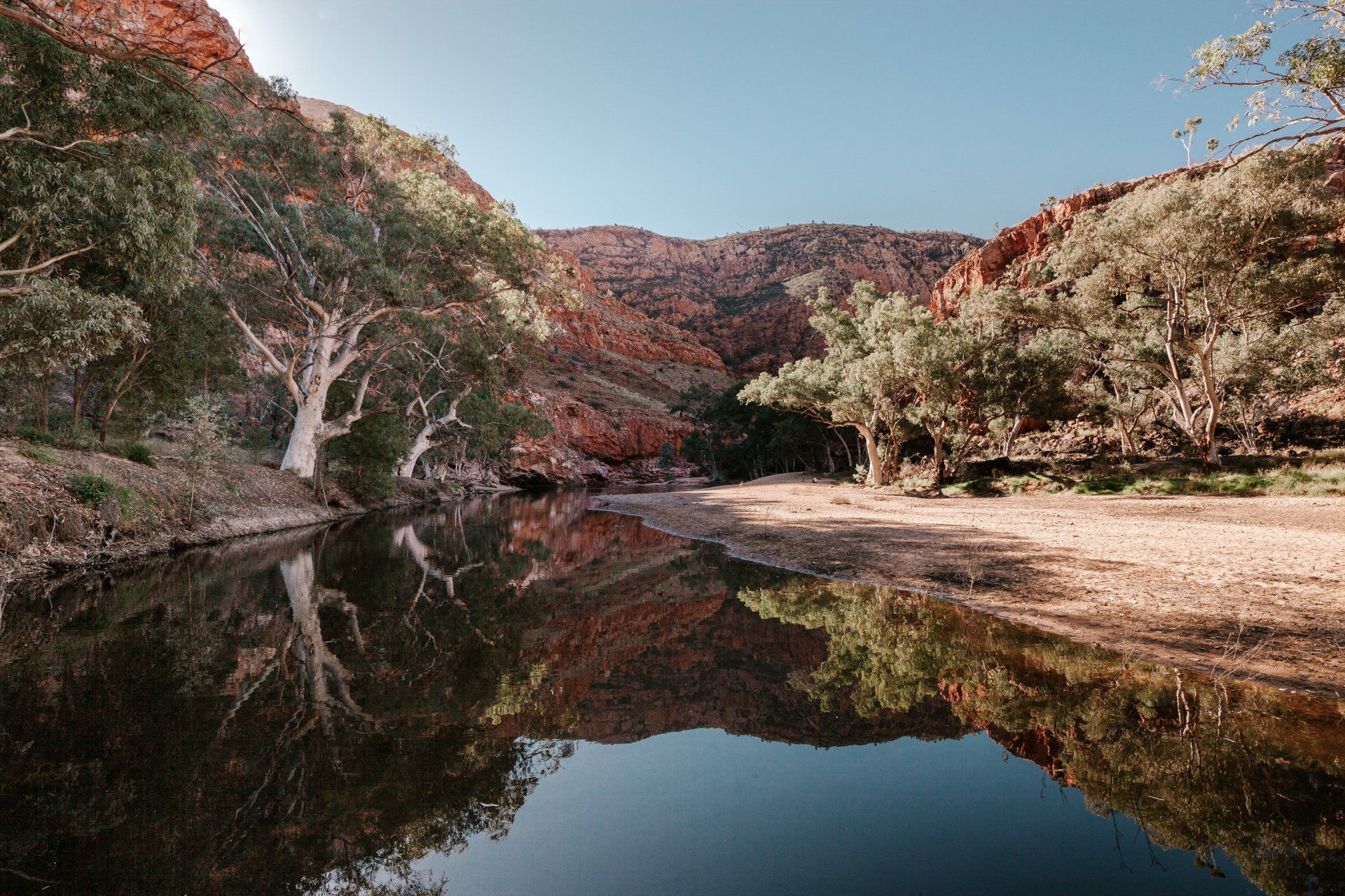 A river surrounded by trees and mountains is reflected in the water.