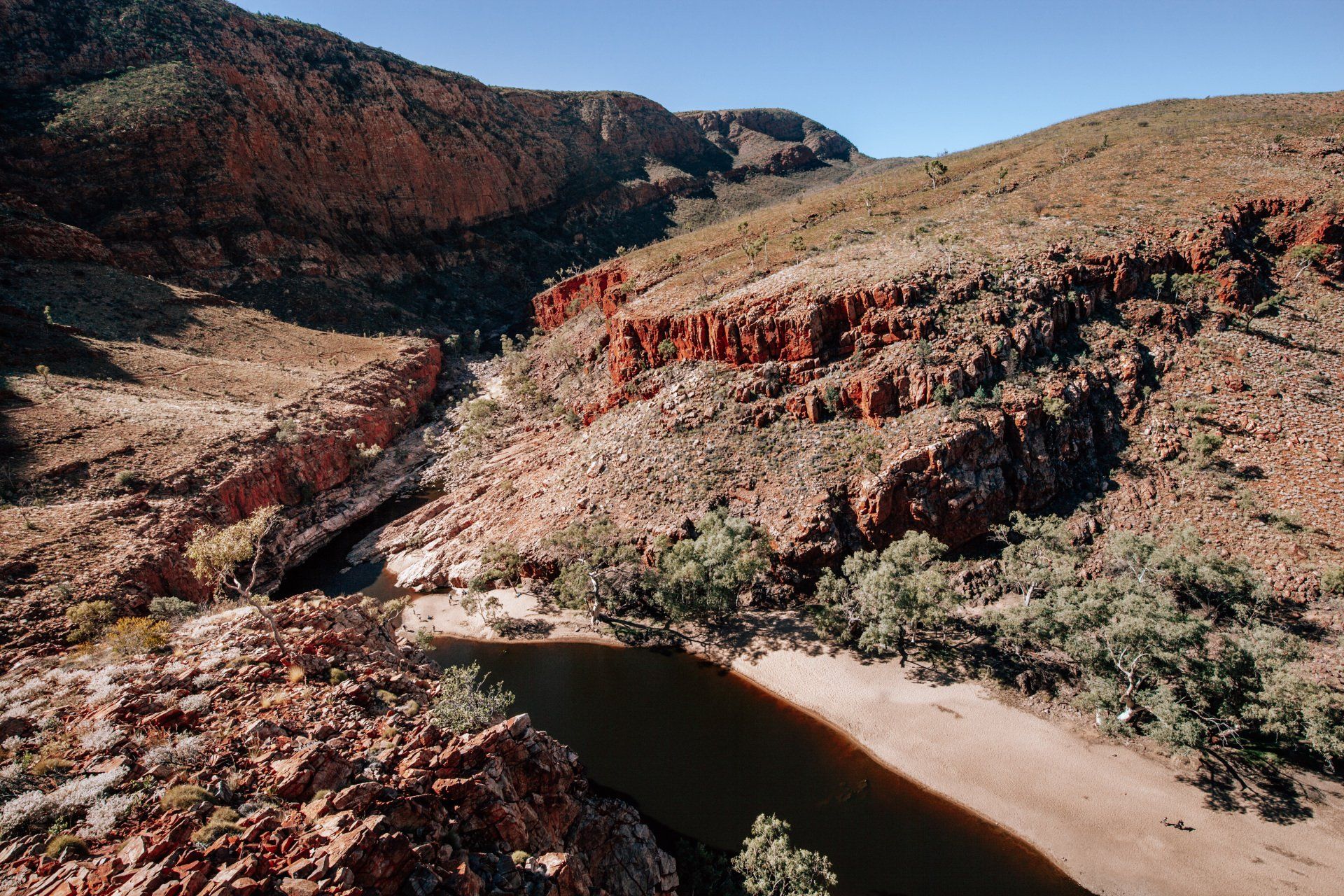 An aerial view of a river in the middle of a desert surrounded by mountains.