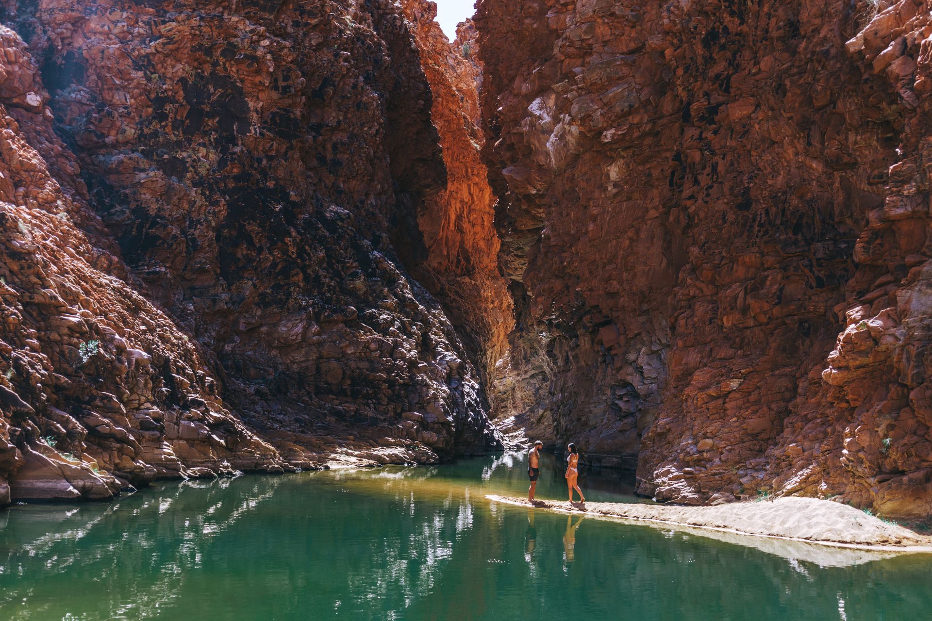 Two people are standing on a bridge over a body of water.