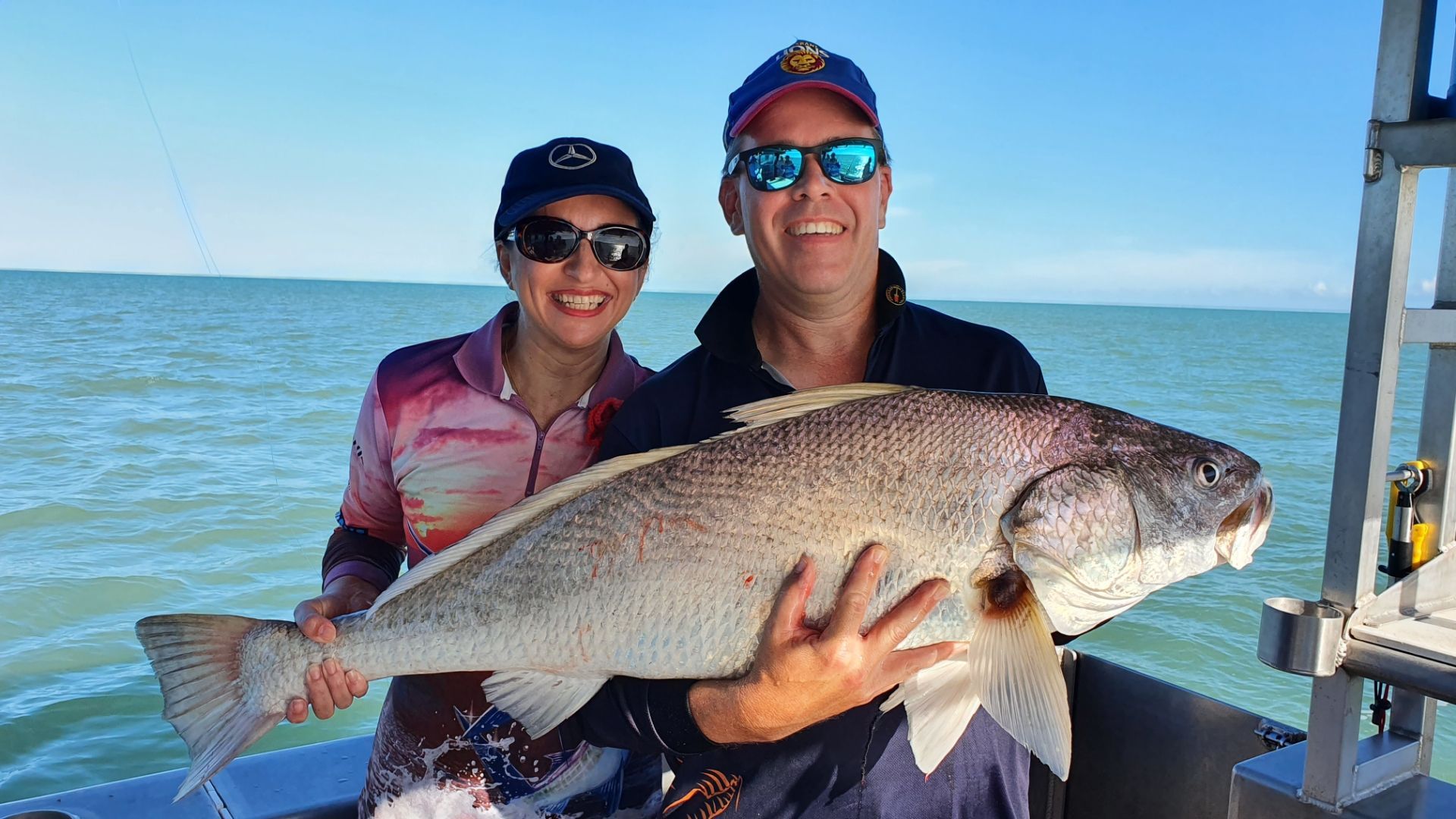 A man and a woman are holding a large fish on a boat.