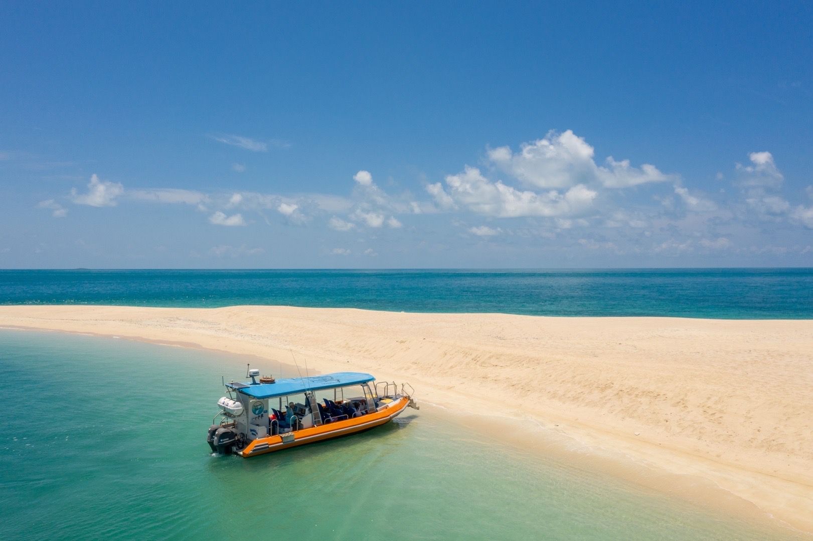 A boat is floating on top of a sandy beach in the ocean.