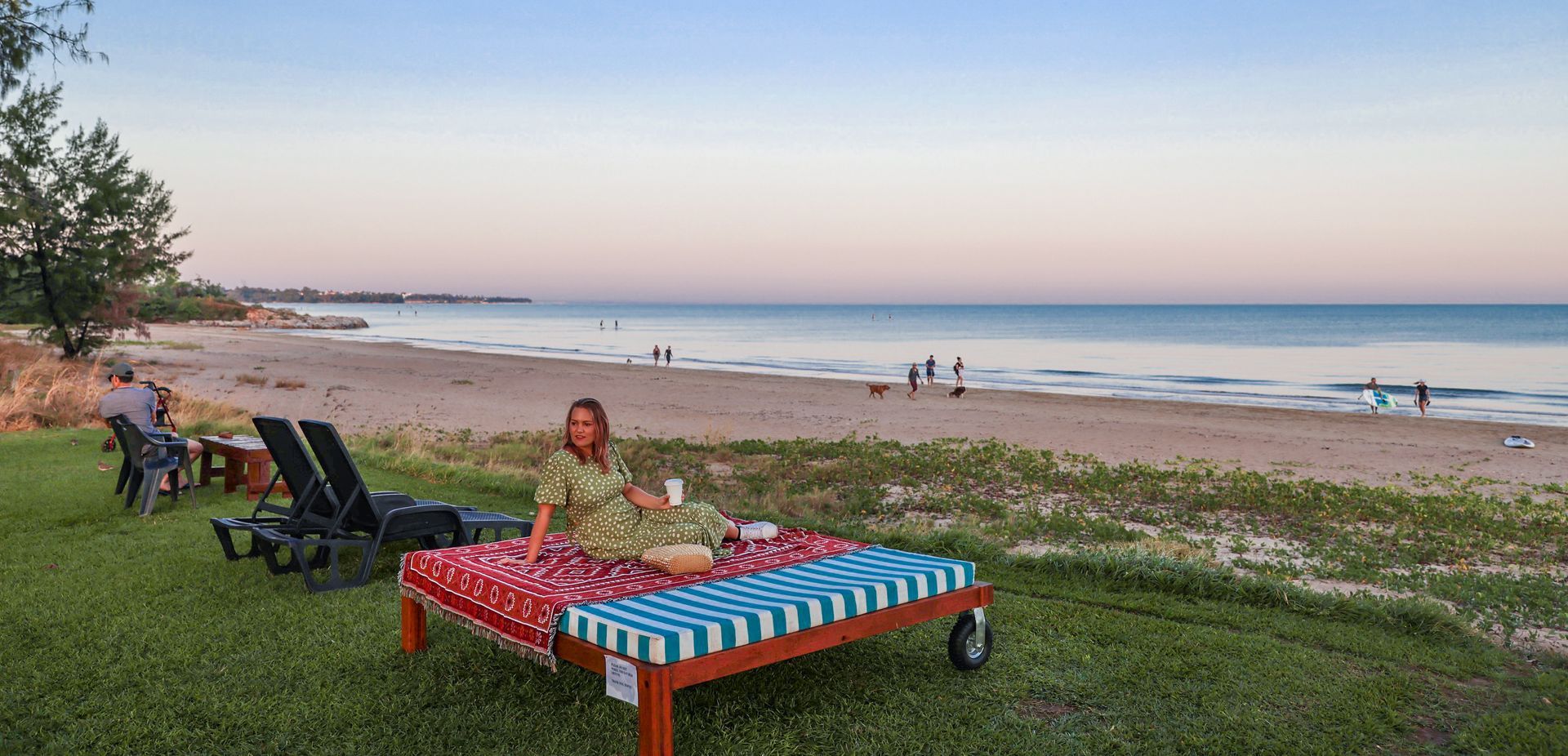 A woman is sitting on a picnic table on the beach.
