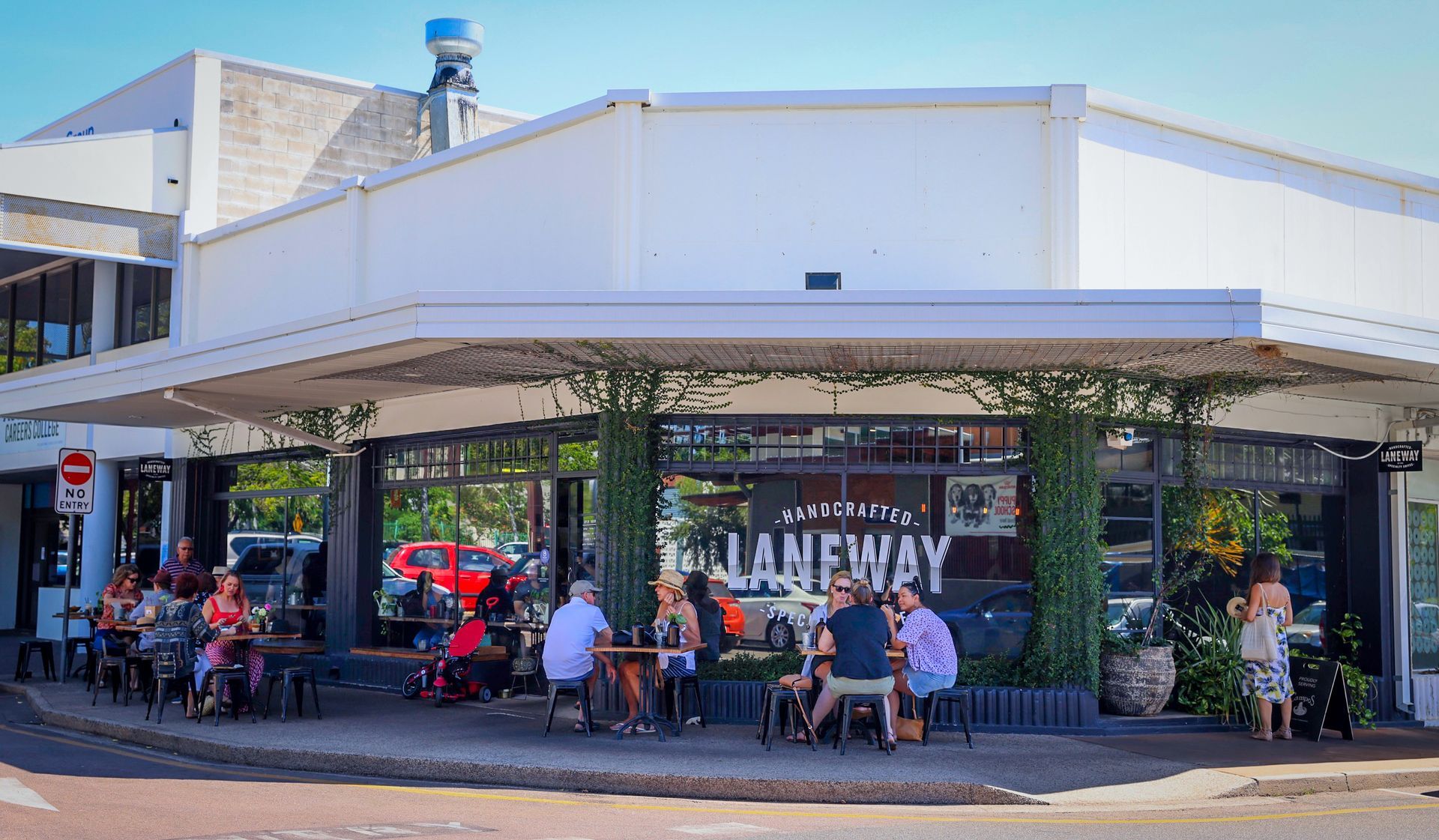 A group of people are sitting at tables outside of a restaurant.