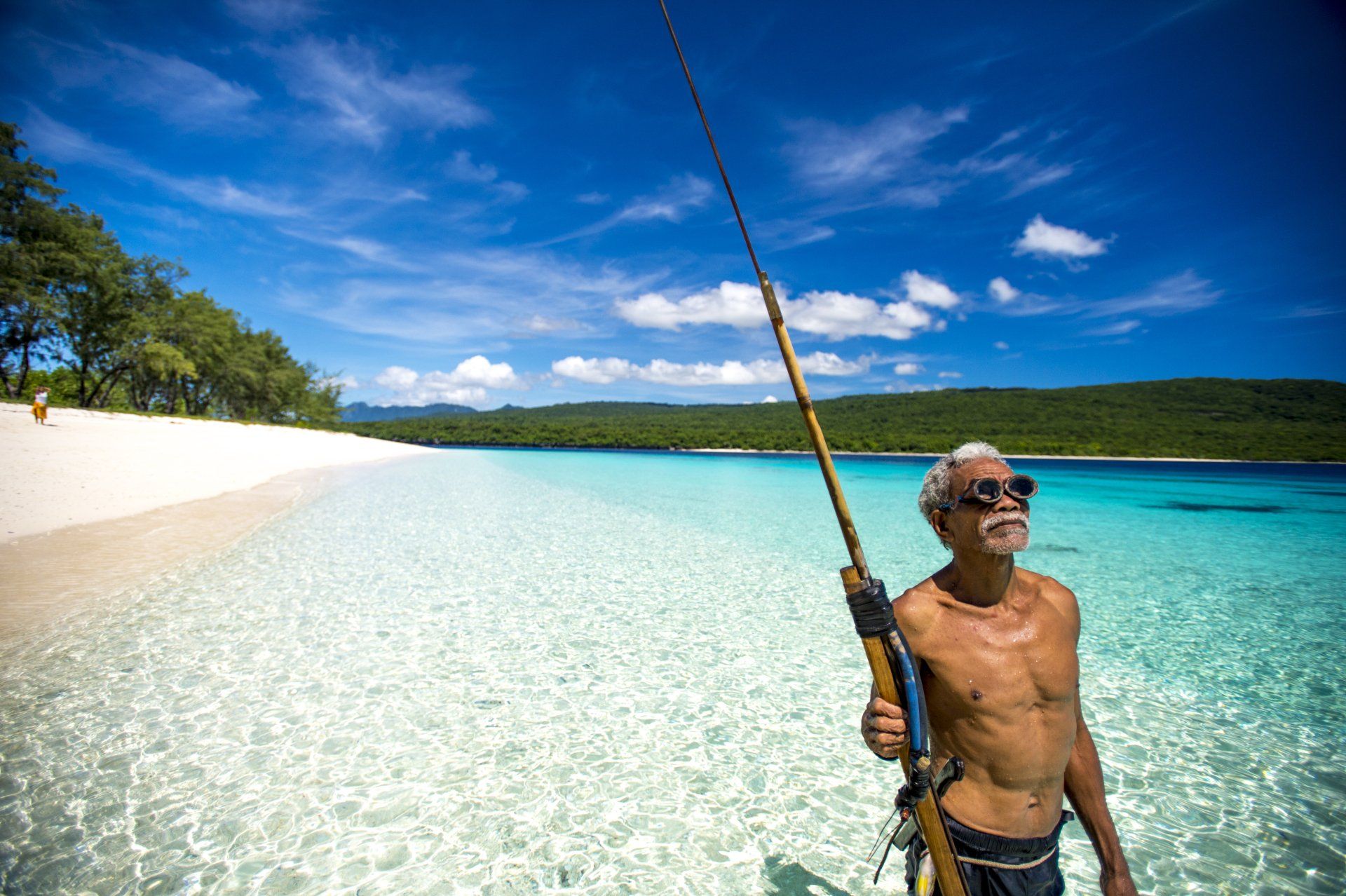 A man is standing in the water holding a fishing rod.