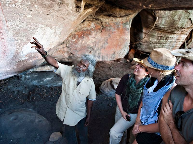 A group of people are looking at a painting on a rock