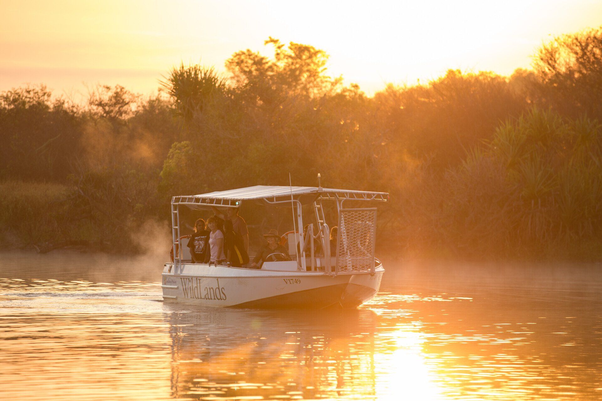 A boat is floating on a river at sunset.