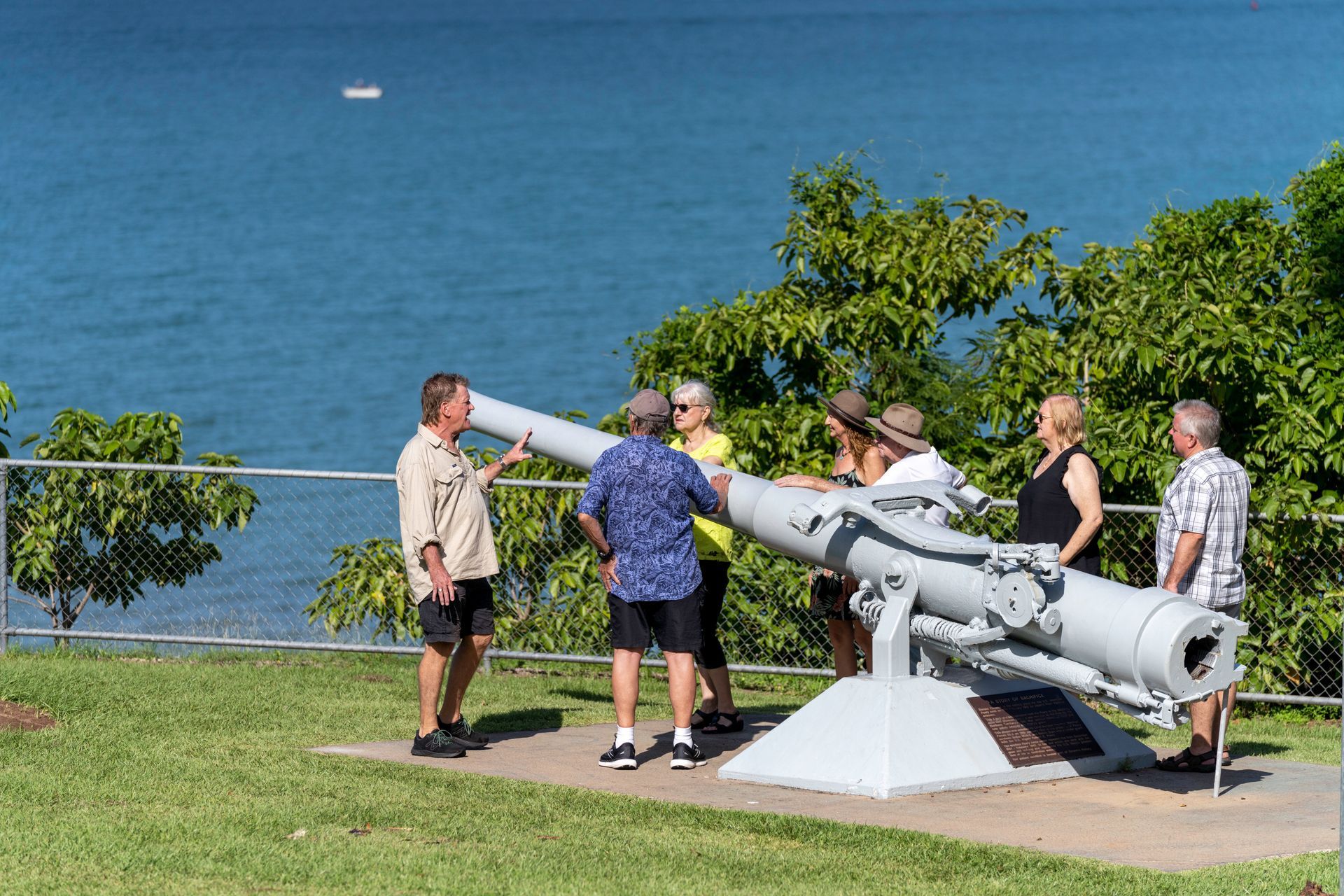 A group of people are standing around a cannon overlooking the ocean.