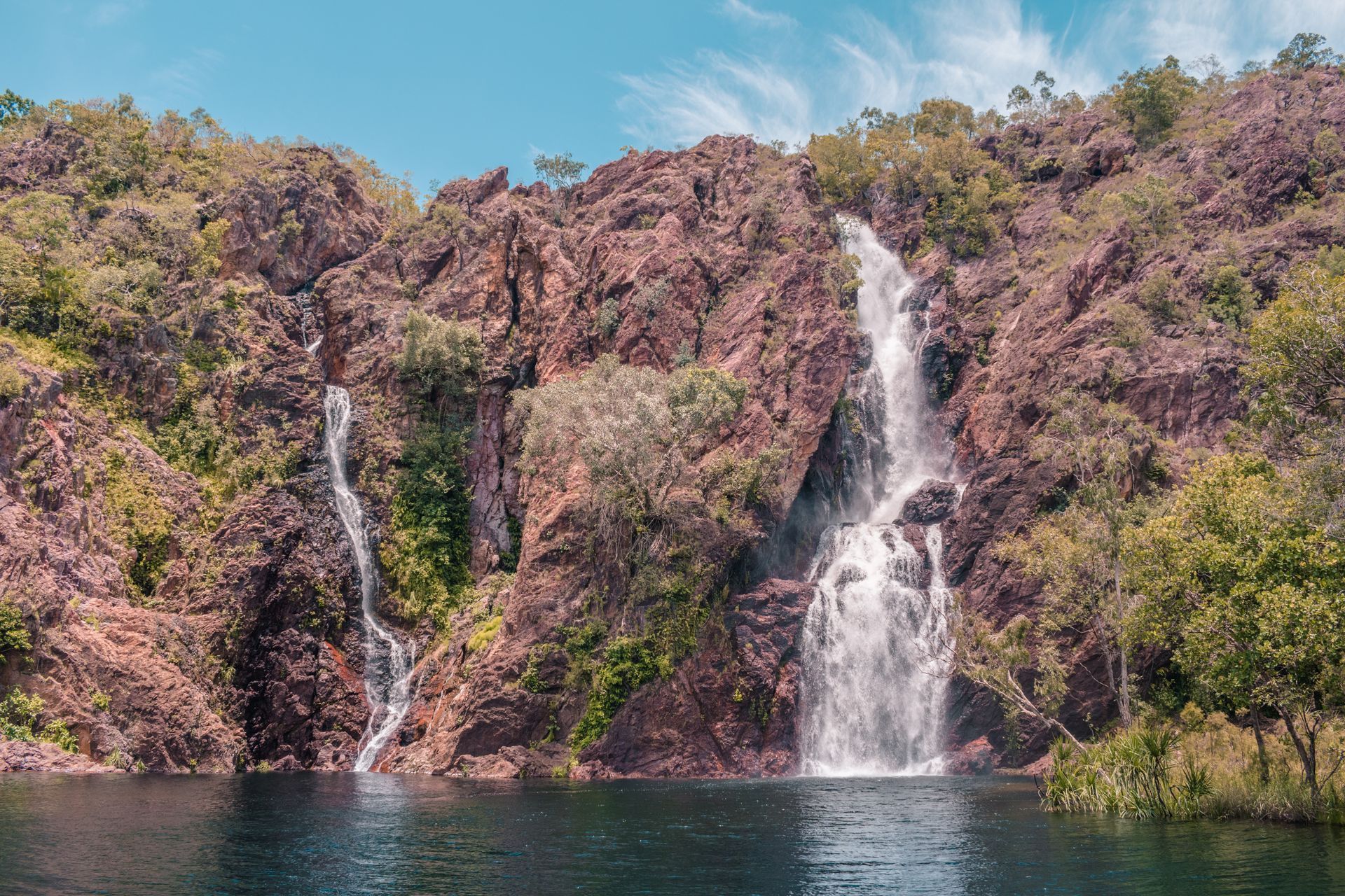 There is a waterfall in the middle of a lake surrounded by trees.