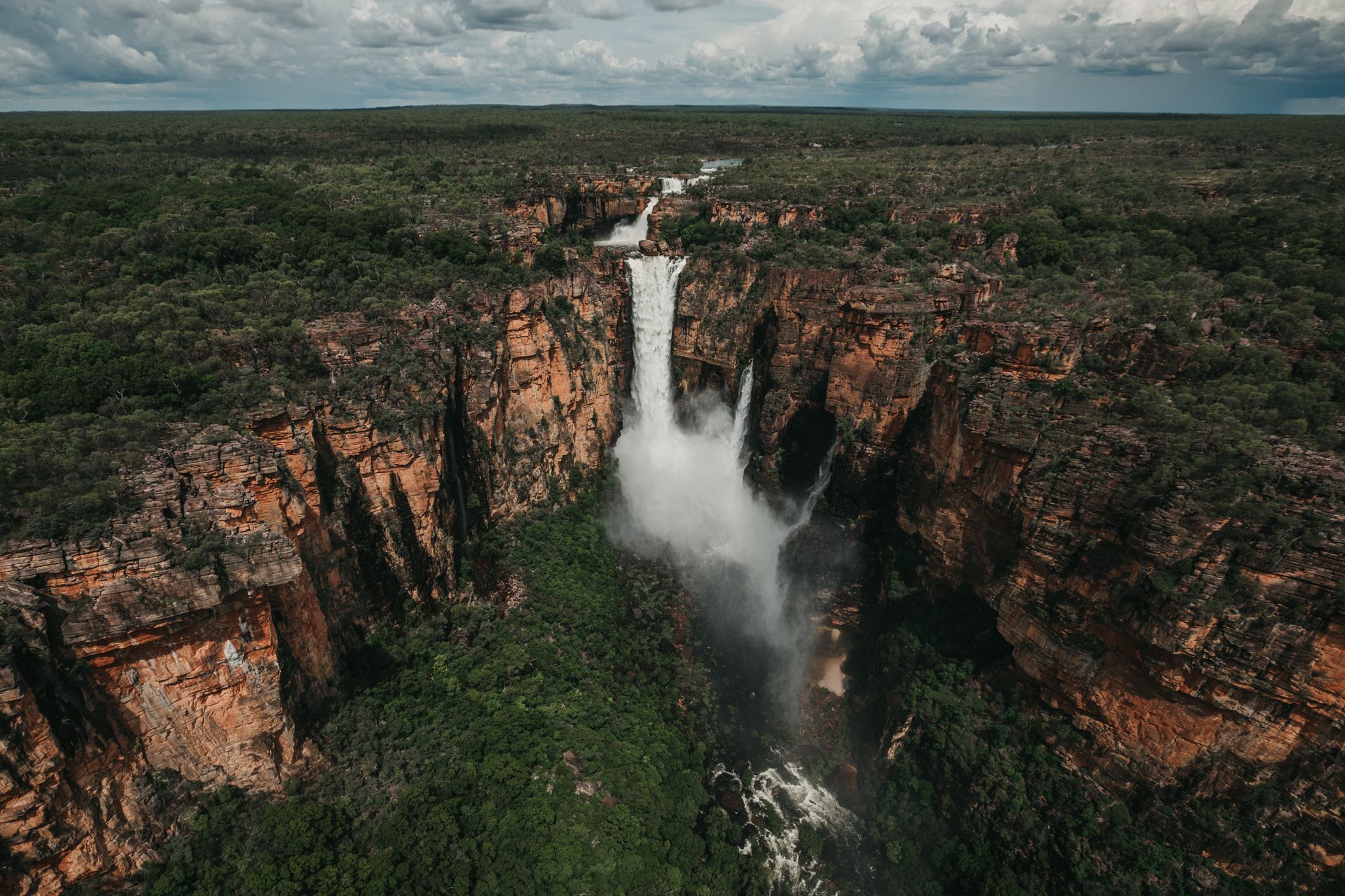 An aerial view of a waterfall in the middle of a forest.