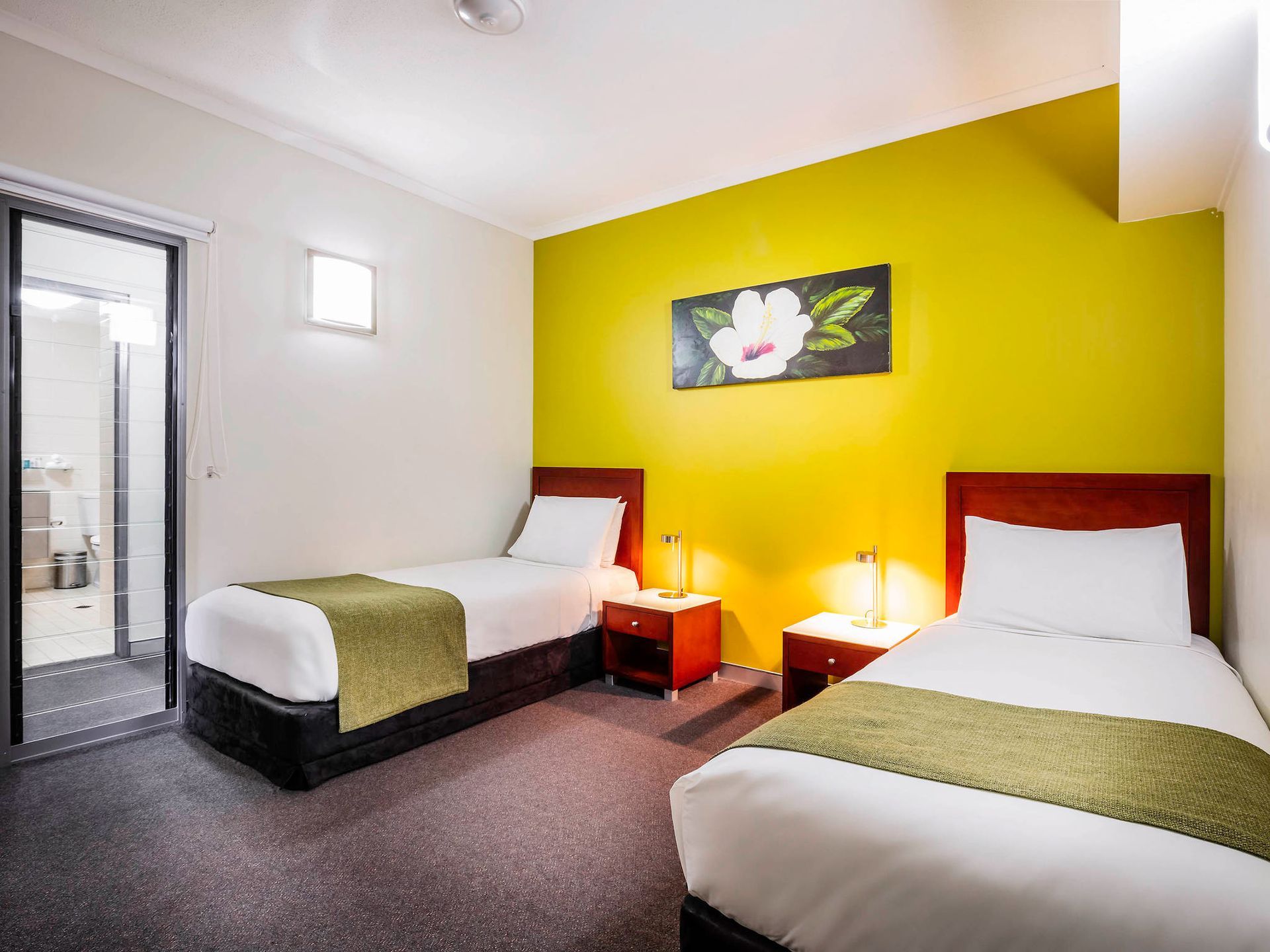 A hotel room with two beds and a yellow wall