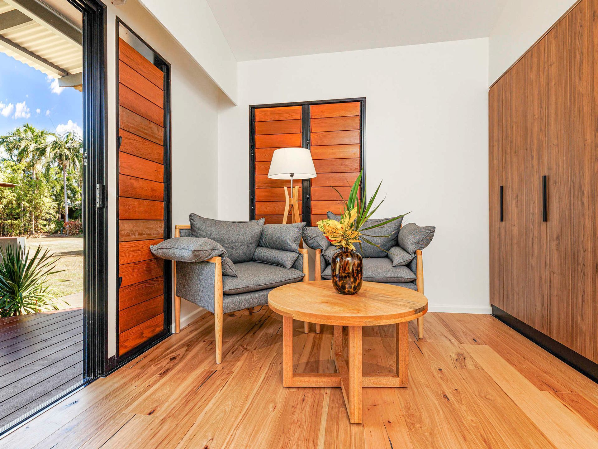A living room with a couch , chairs , a table and a lamp.