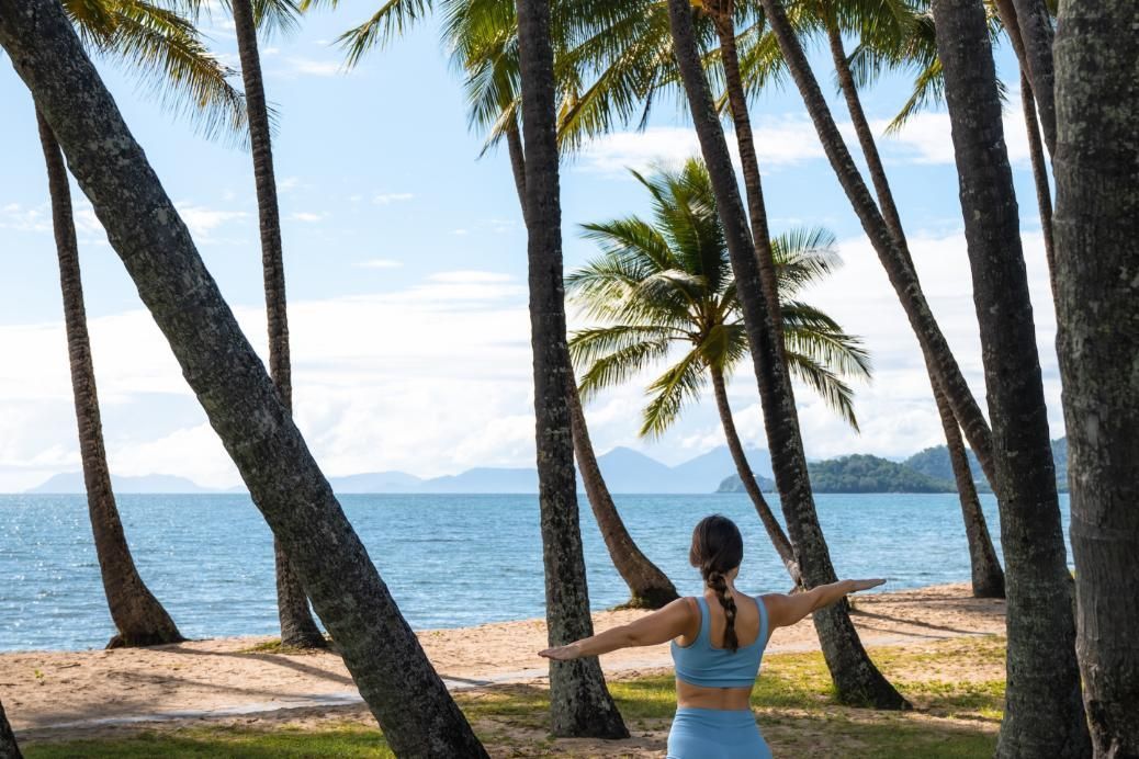 A living room with a couch , table , refrigerator and kitchen.