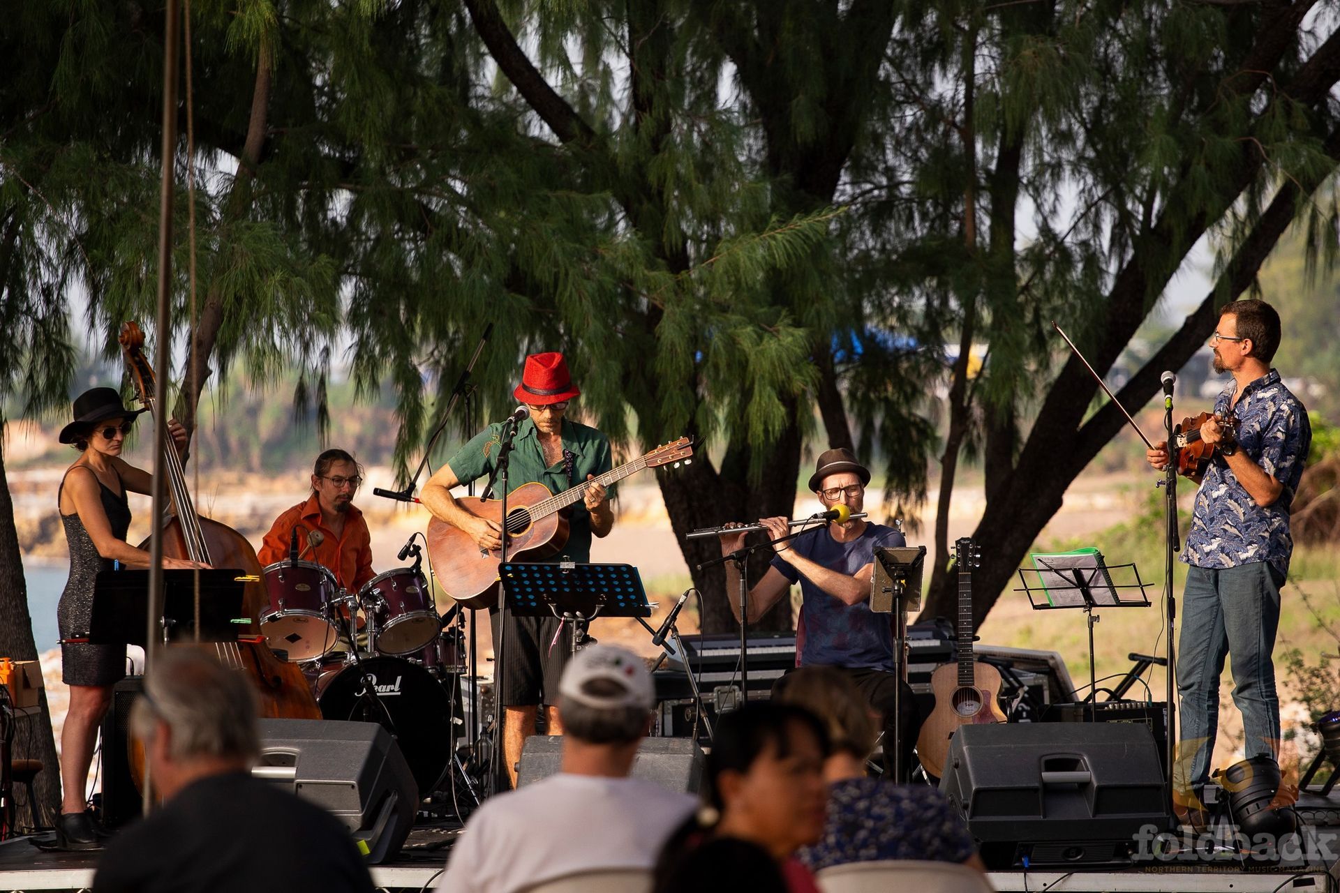 A group of people playing instruments on a stage in front of a crowd.