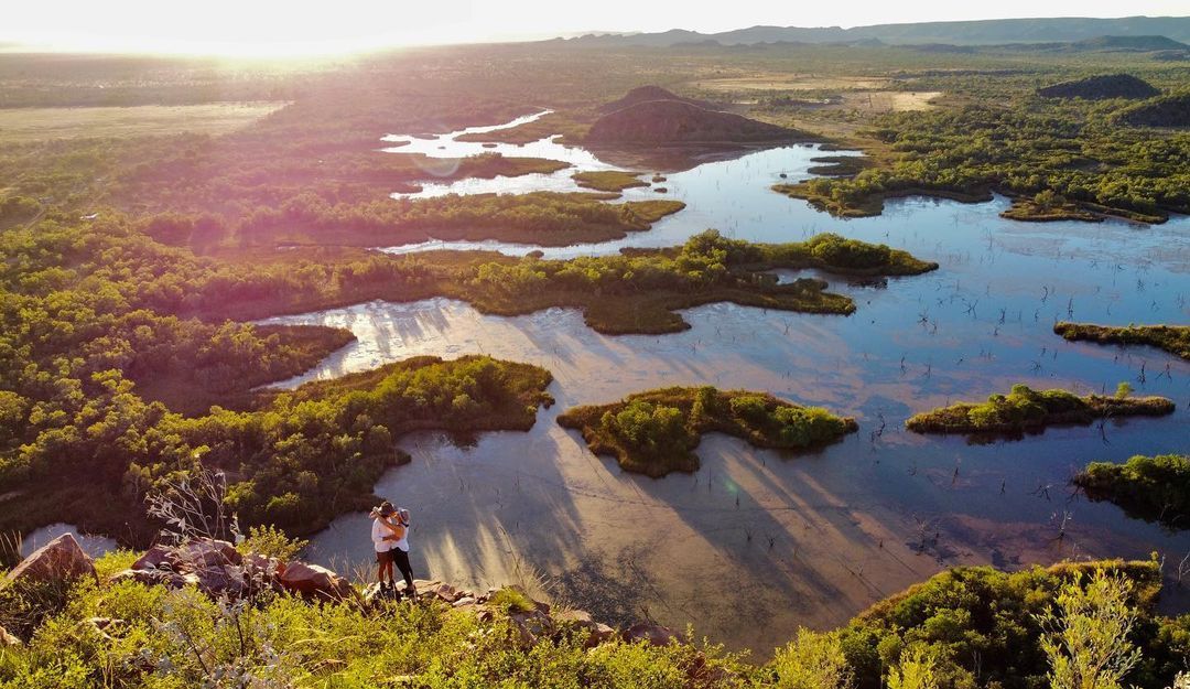 A person is standing on top of a hill overlooking a lake.