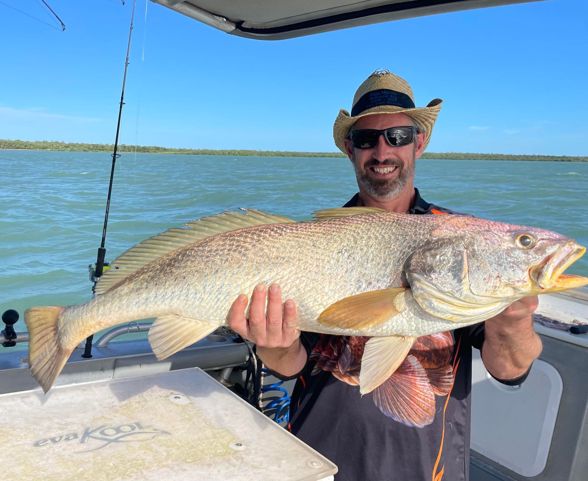 A man is holding a large fish on a boat.