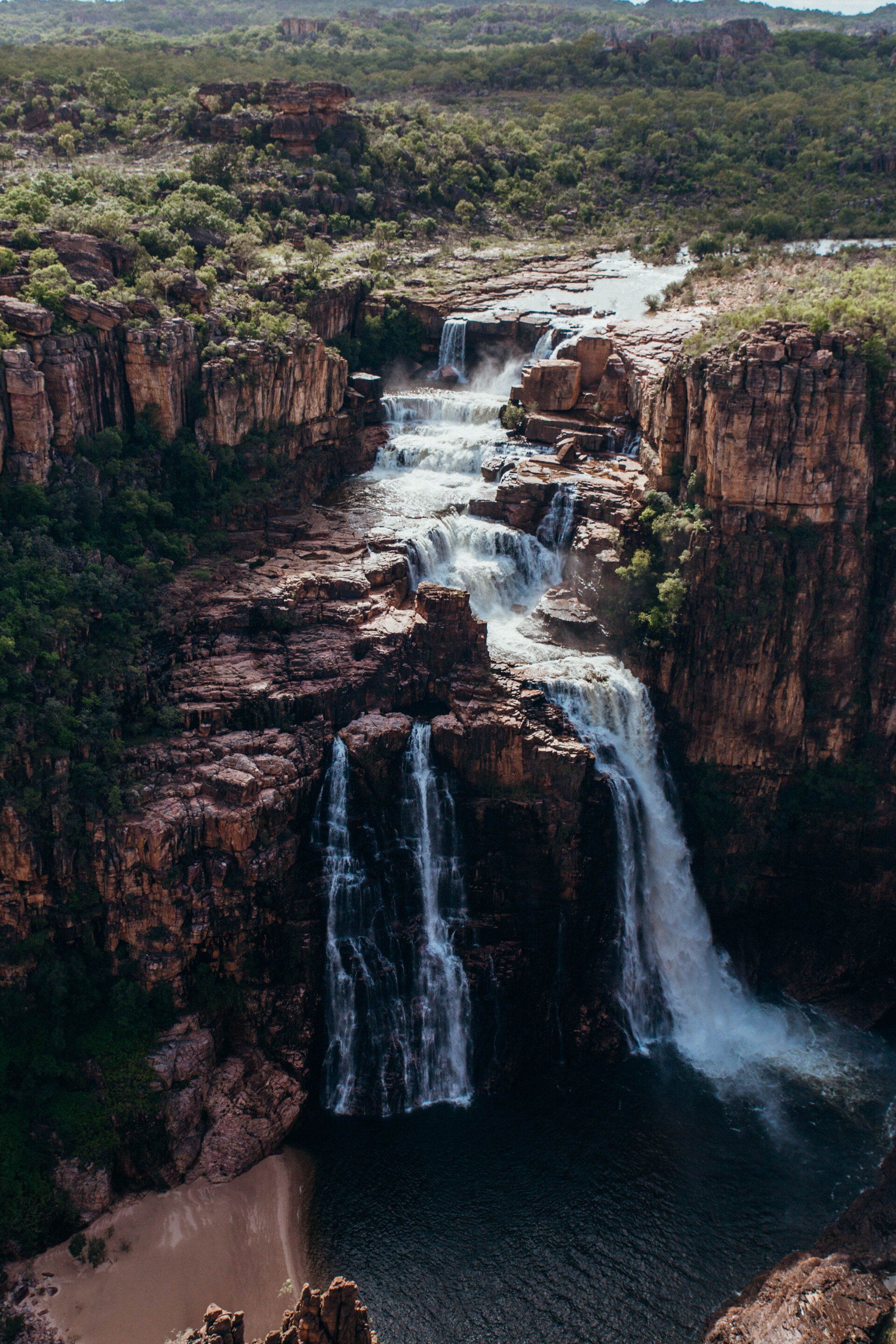An aerial view of a waterfall surrounded by rocks and trees.