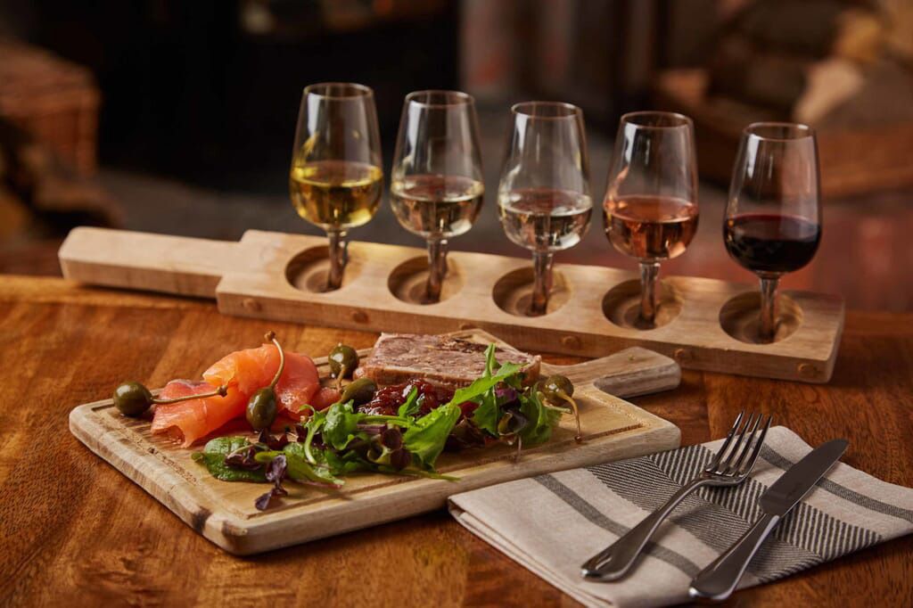 A tray of food and wine glasses on a wooden table