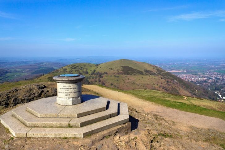 A statue on top of a hill with a view of a city.