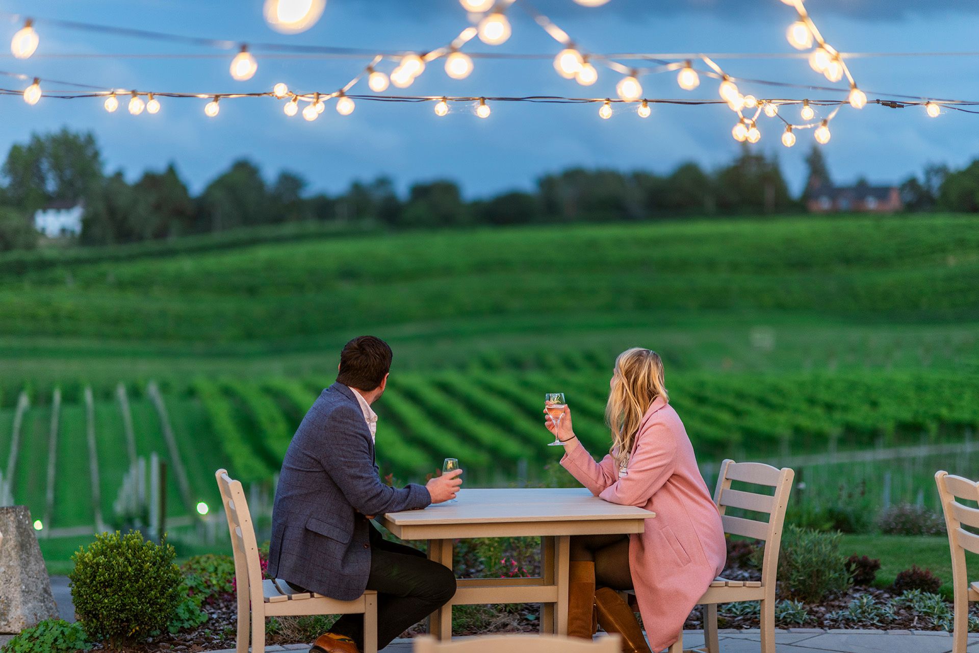 Couple relaxing with wine on a balcony overlooking the vineyard at Three Choirs Vineyards hotel