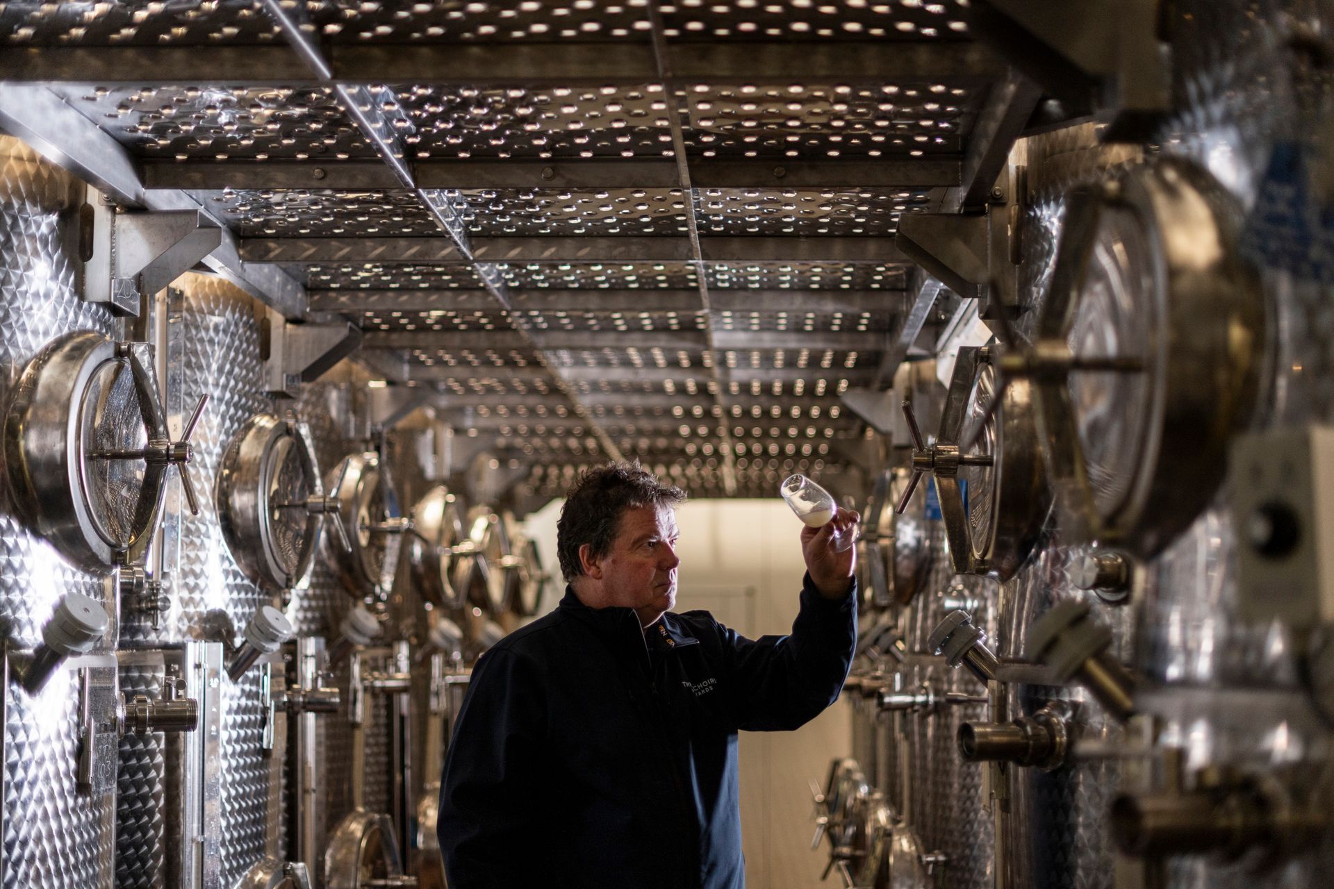 a man is holding a glass of wine in a warehouse