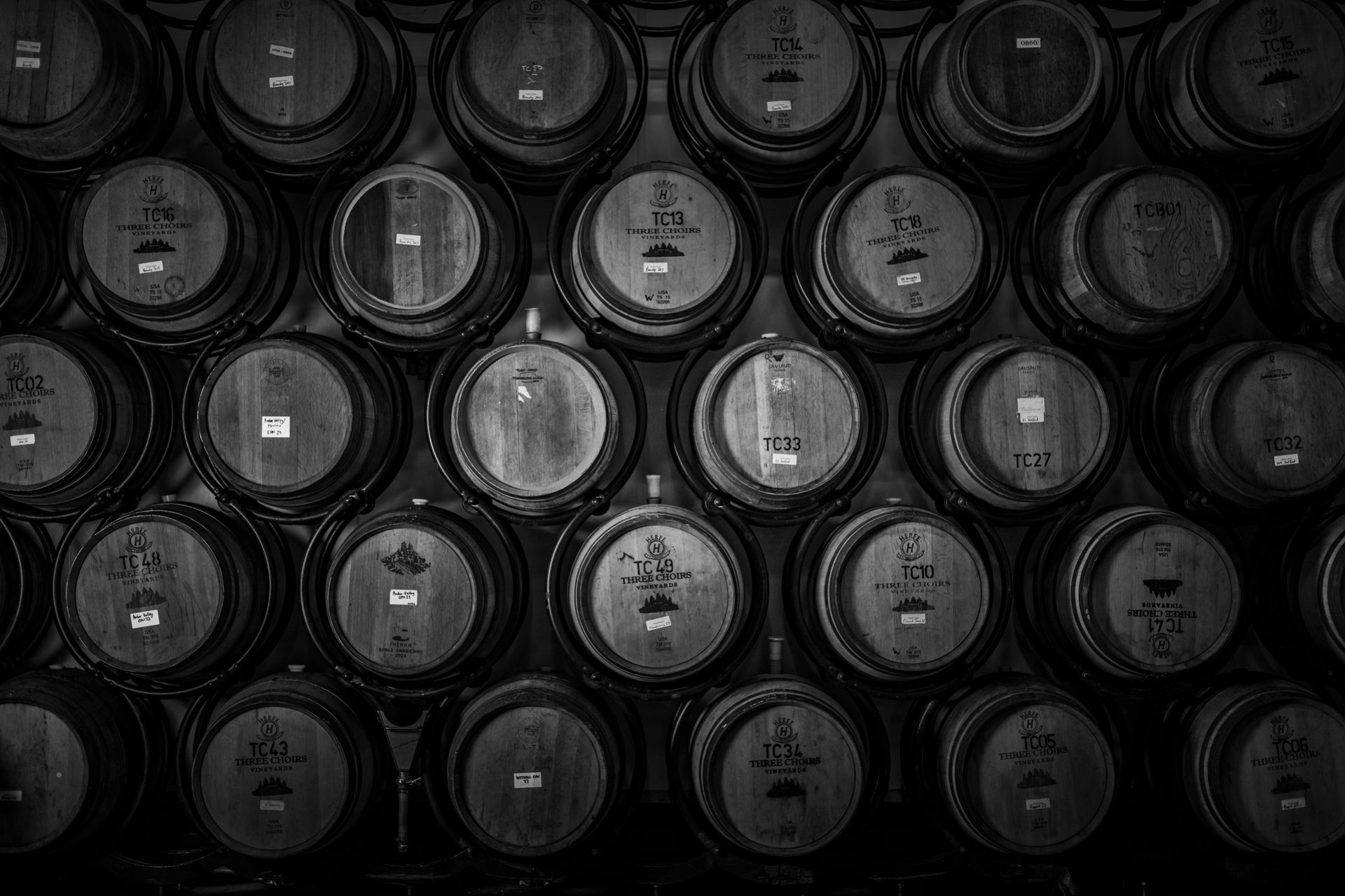 Several bottles of wine are lined up on a wooden table, labelled Three Choirs Vineyards