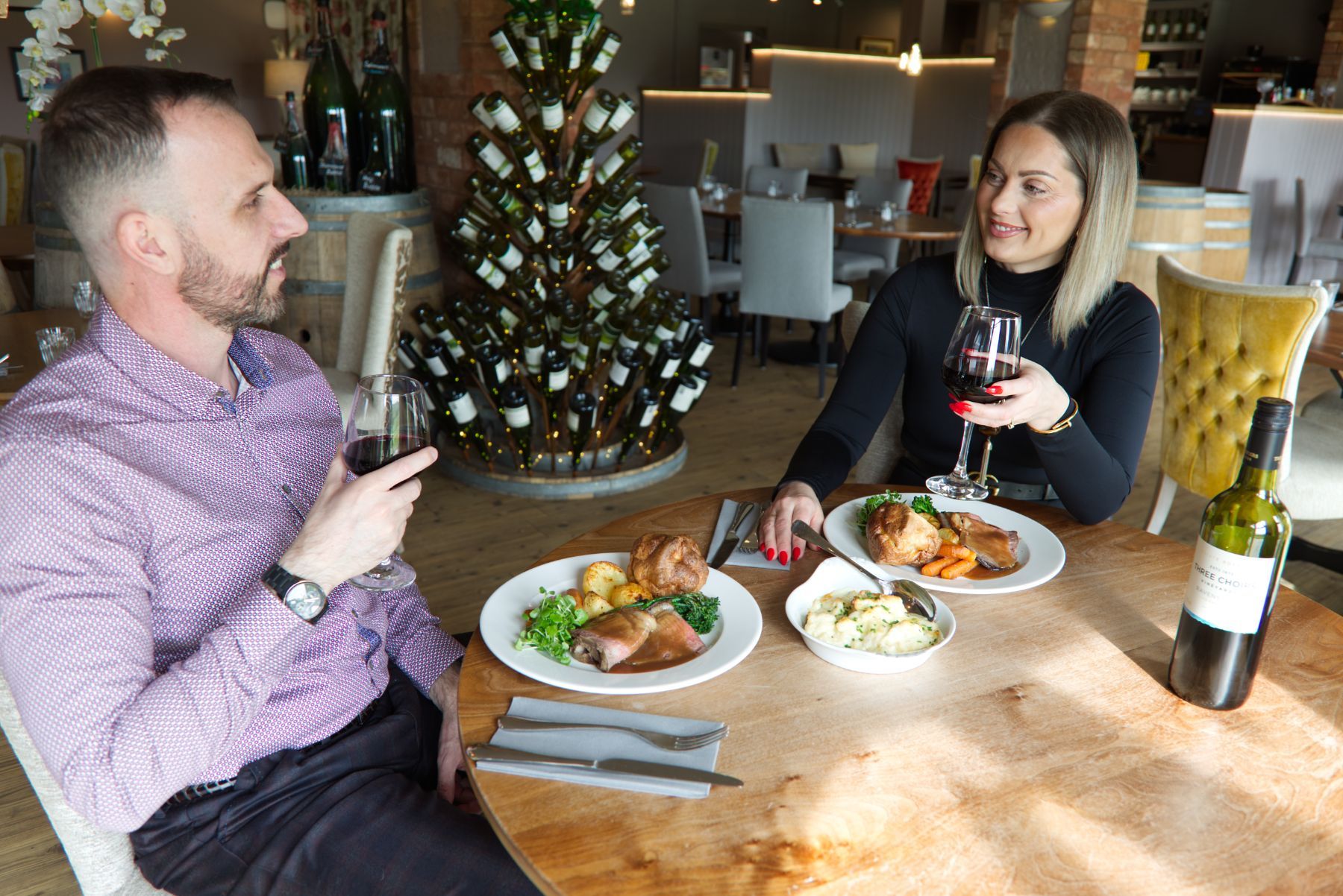a wooden cutting board with food and a glass of wine on a table .