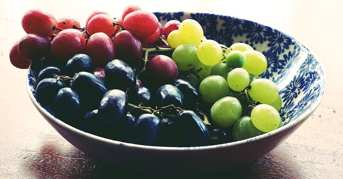 A blue and white bowl filled with grapes of different colors