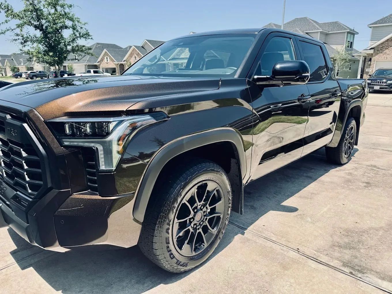 Brown Toyota Tundra pickup truck parked on a driveway in a residential area on a sunny day.