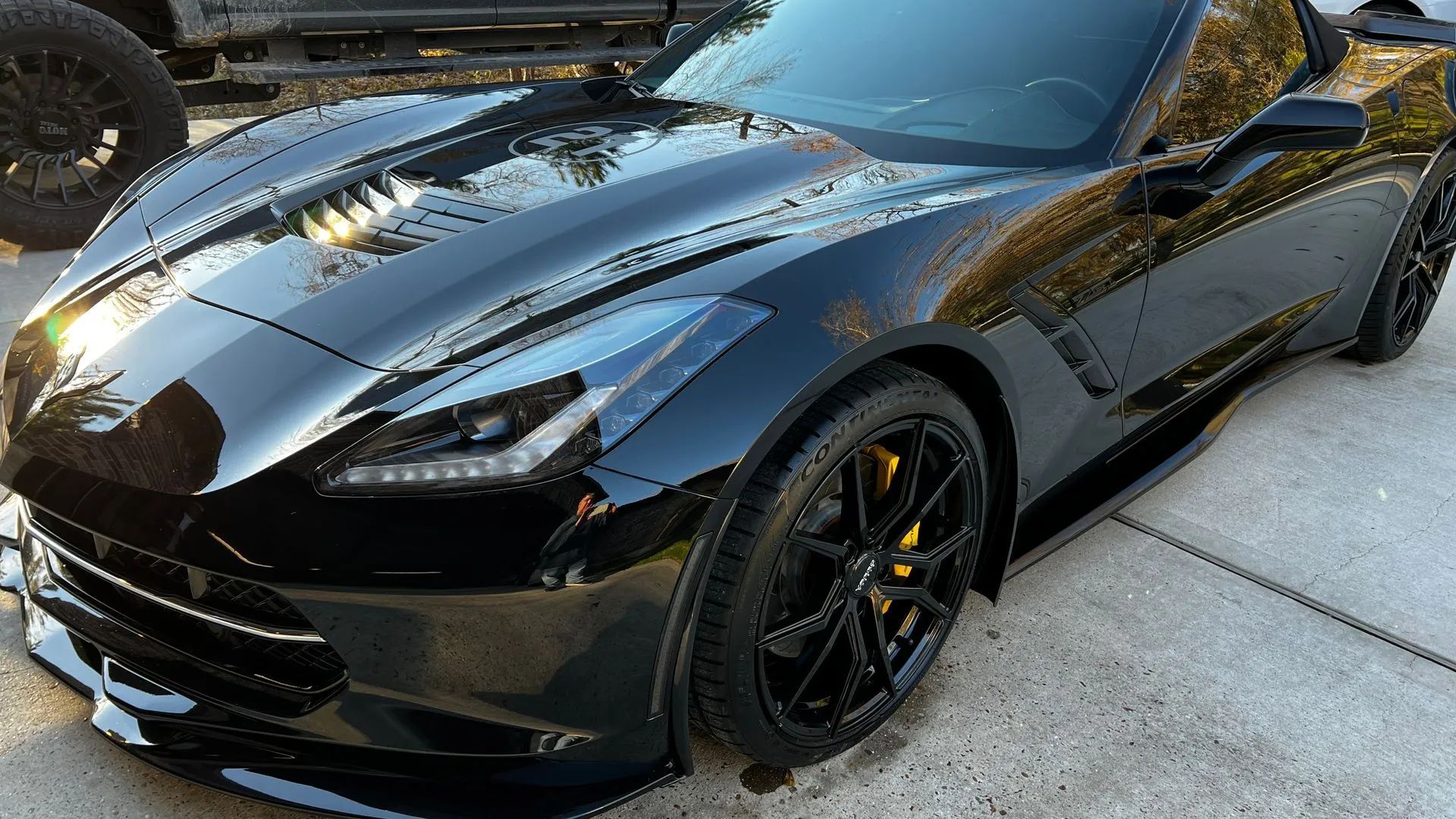 Black Corvette sports car, parked outside. Shiny, black paint reflects light.