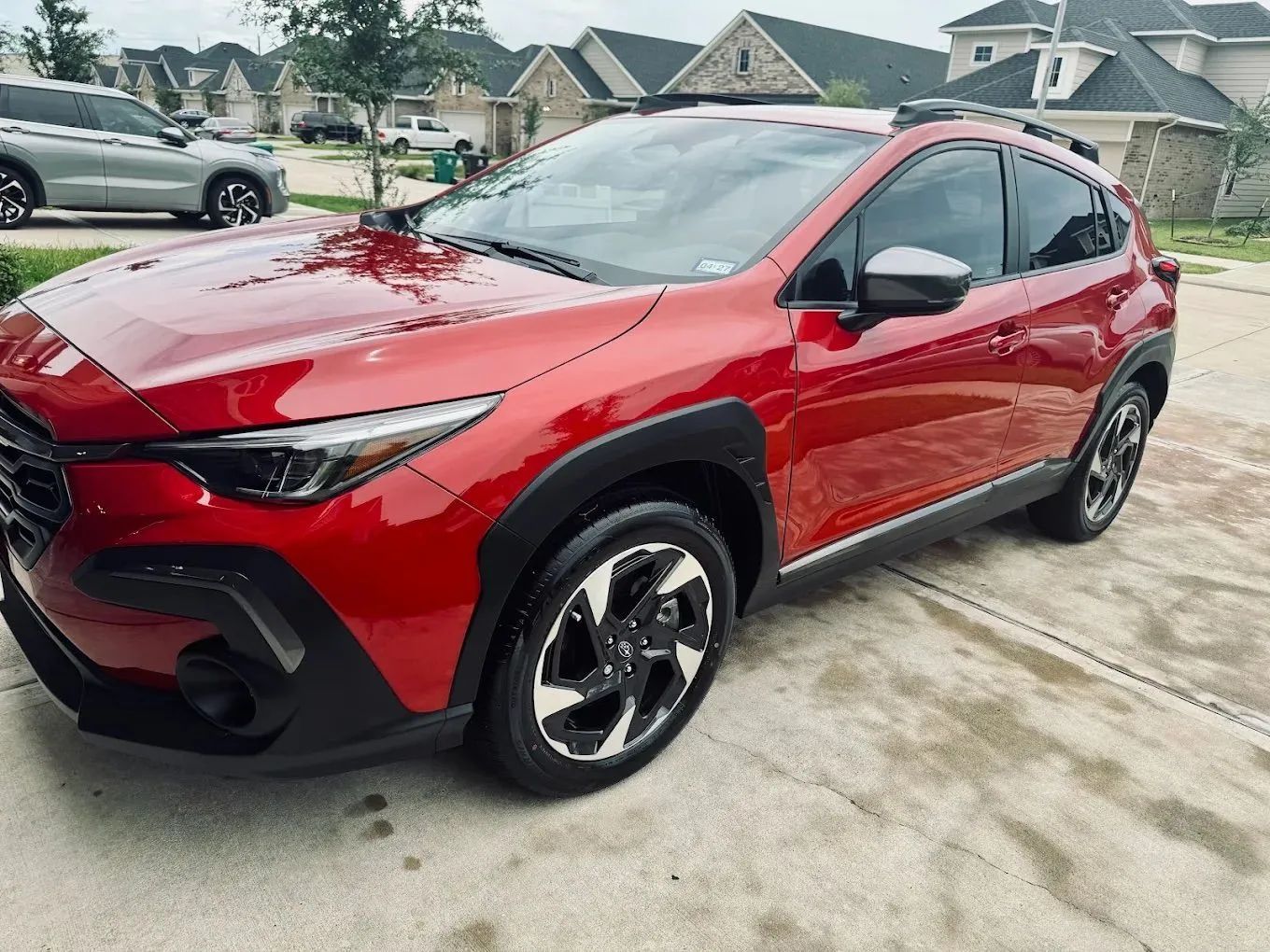 A red Subaru Crosstrek parked on a residential driveway on a cloudy day.