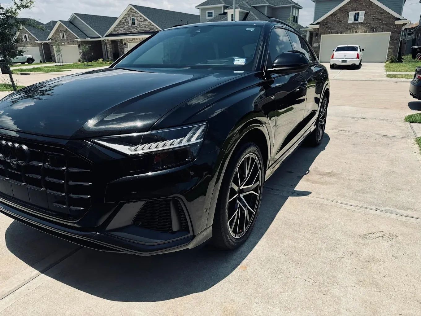 A black Audi Q8 SUV parked on a residential driveway in a suburban neighborhood.