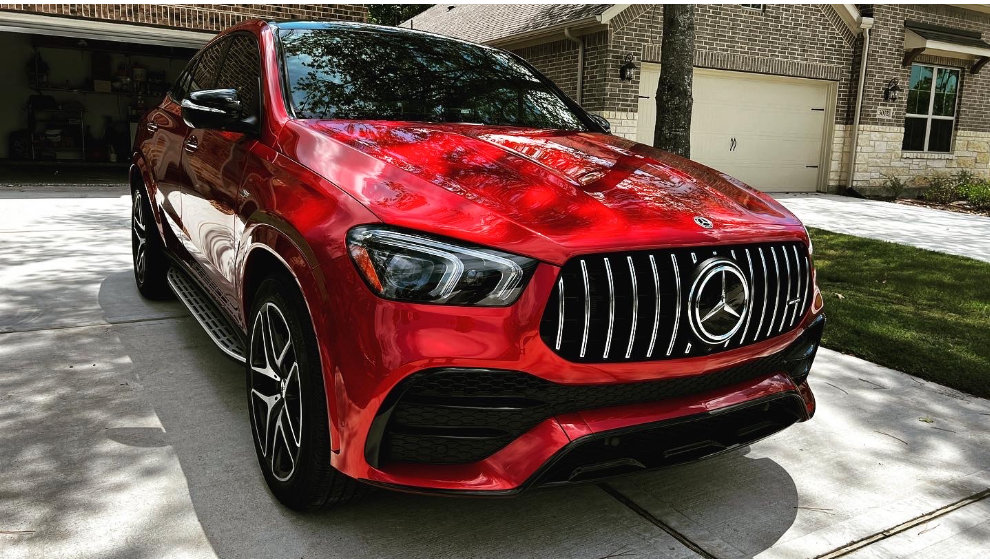 A bright red Mercedes-Benz SUV parked on a concrete driveway in front of a house.