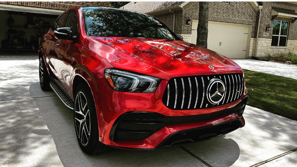 A red Mercedes-Benz GLE SUV parked in a residential driveway, showcasing its signature front grille and sporty design.