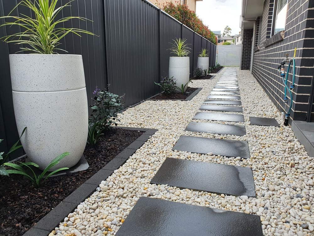 A Walkway And Potted Plants Along The Side Of A House — Green Envy Landscape & Garden Services In Cameron Park NSW