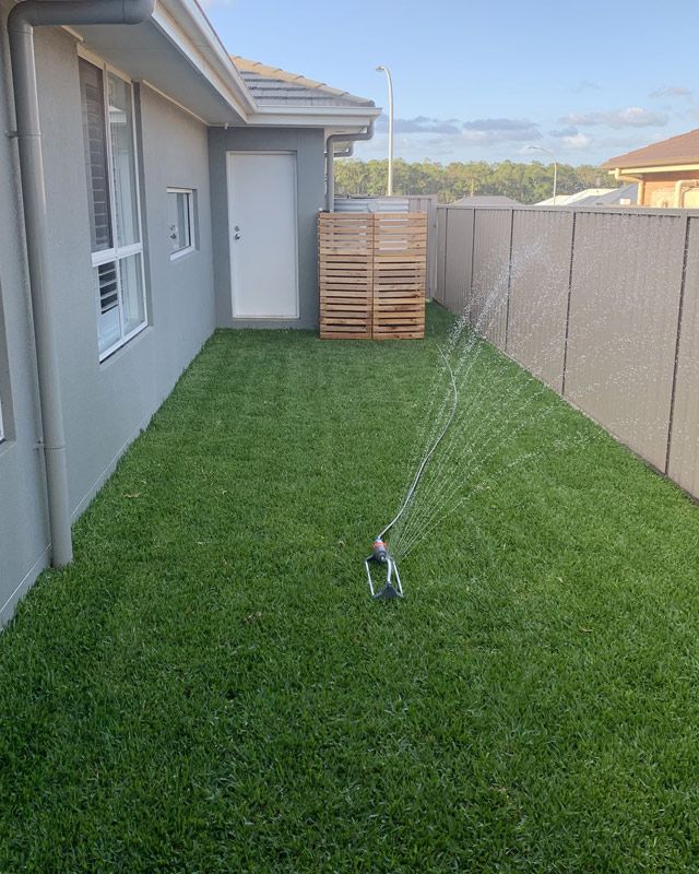 A Lawn Sprinkler Is Spraying Water On A Lush Green Lawn — Green Envy Landscape & Garden Services In Cameron Park NSW