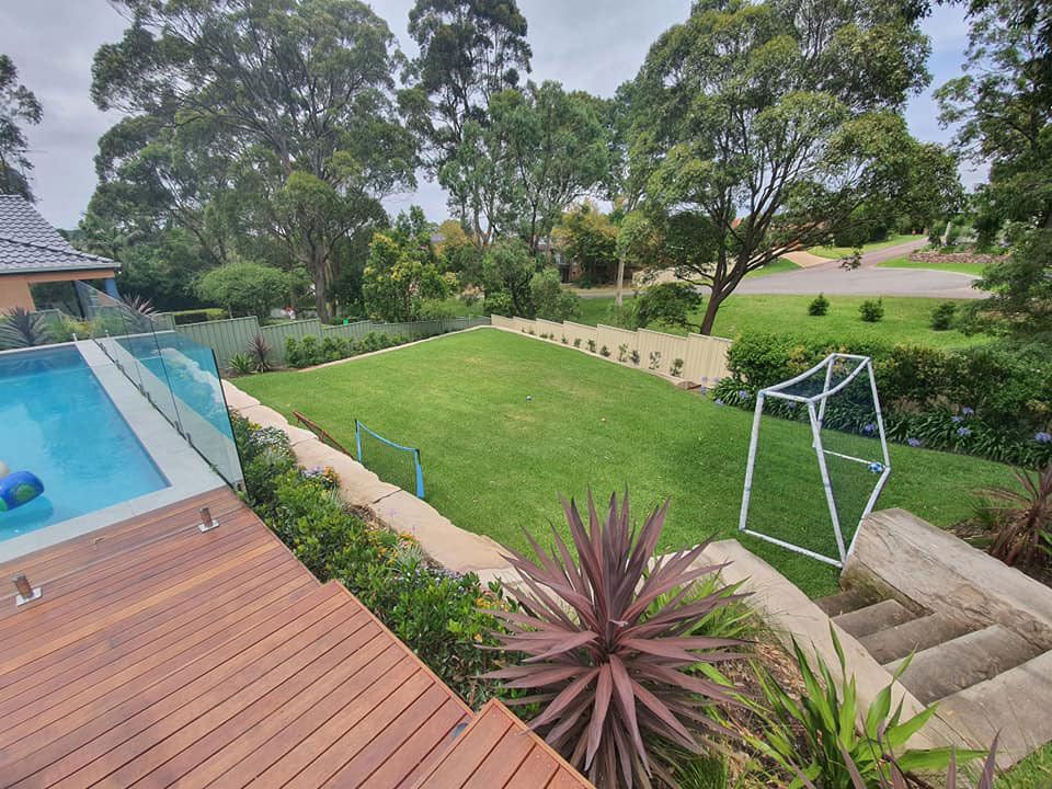 There Is A Swimming Pool In The Backyard With A Wooden Deck — Green Envy Landscape & Garden Services In Cameron Park NSW