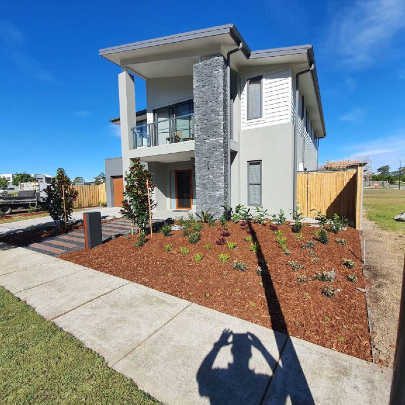 A Shadow Of A Person Is Cast On The Sidewalk In Front Of A House — Green Envy Landscape & Garden Services In Cameron Park NSW